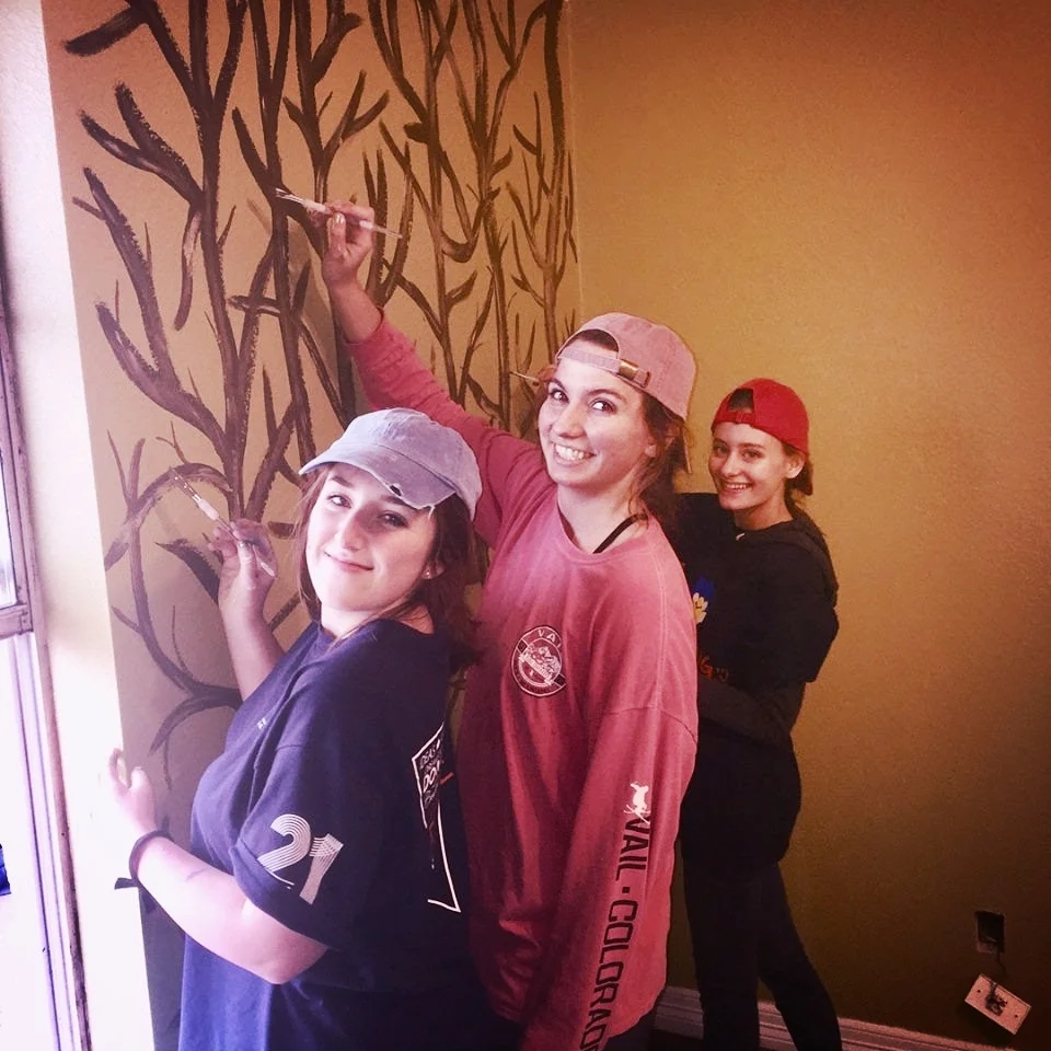 Girls painting trees on wall Haiker Home.jpg