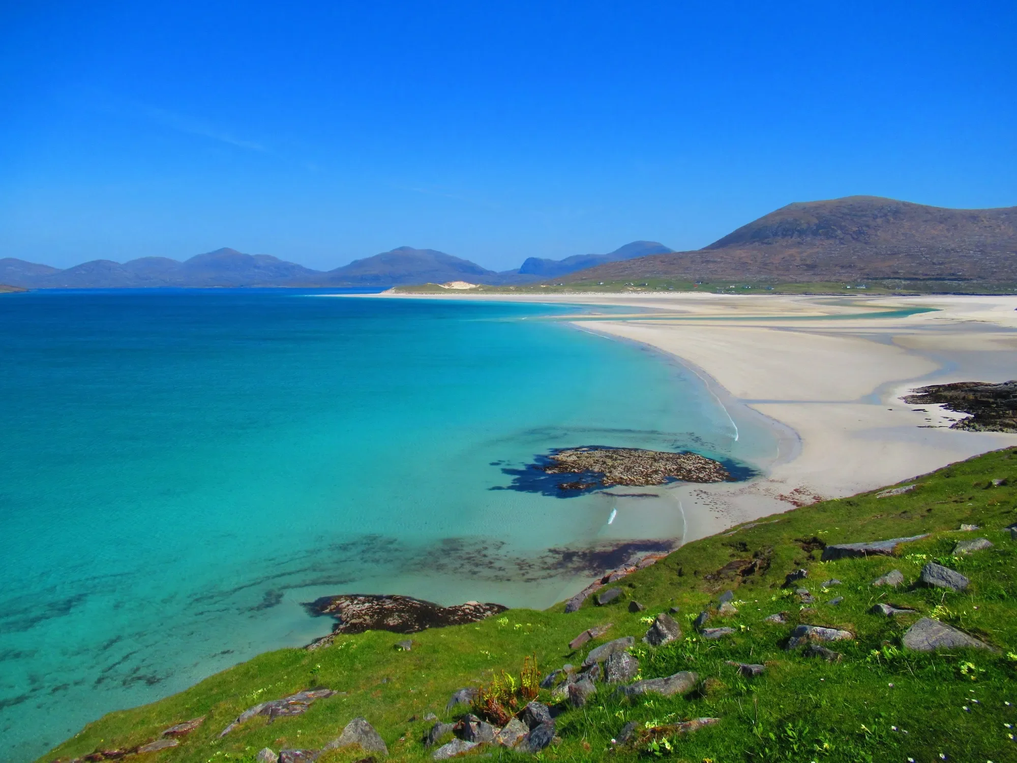 Luskentyre Beach on the Isle of Harris with turquoise water, white sand and mountain views in the Scottish Highlands.