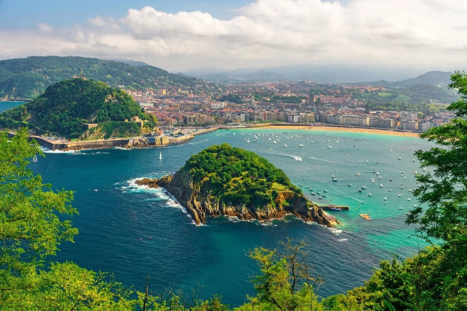 View over La Concha bay in San Sebastián with turquoise water, boats and green hills along Spain’s Basque coast