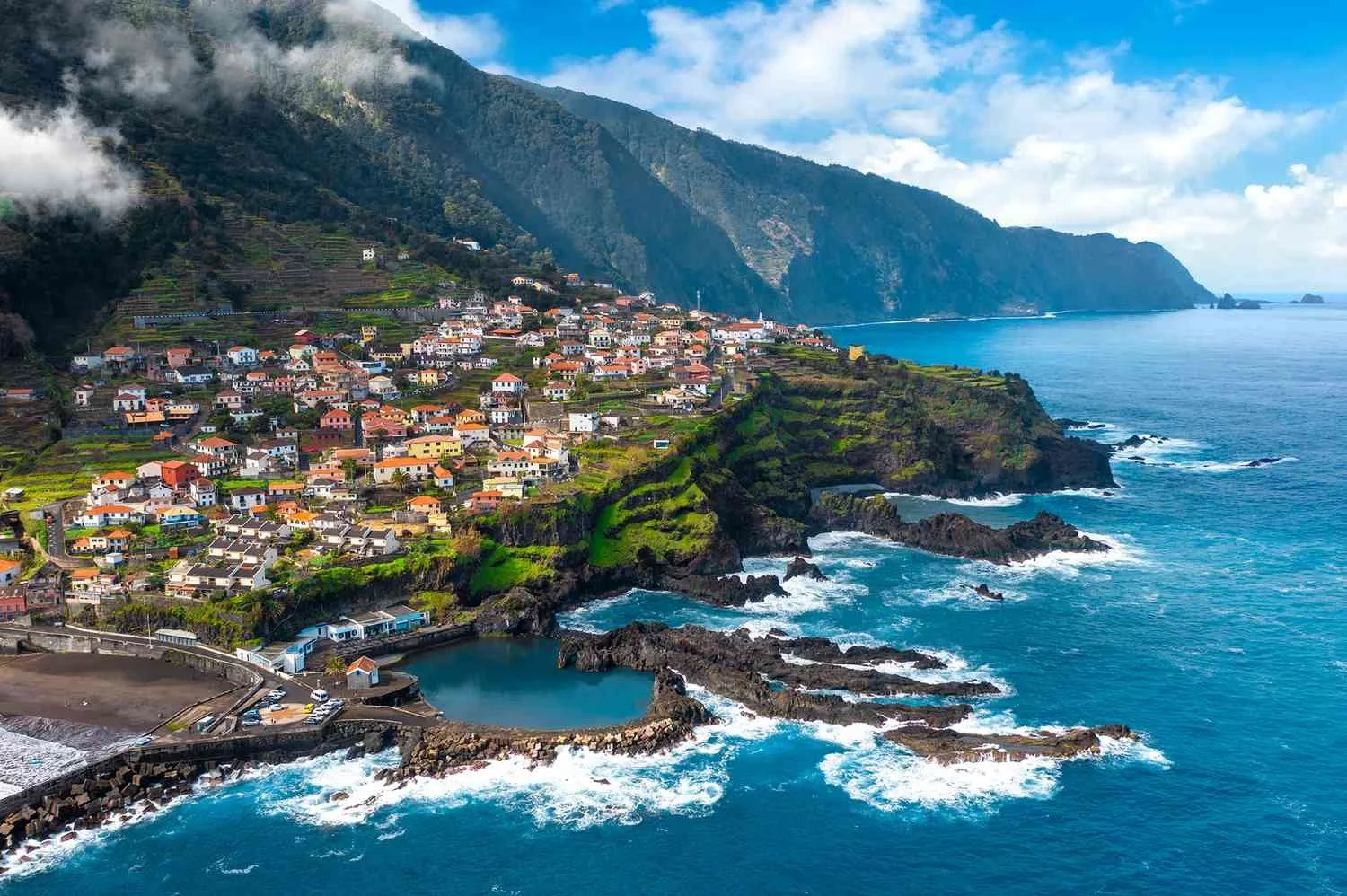 : Madeira coastline with mountain village, dramatic cliffs and Atlantic Ocean