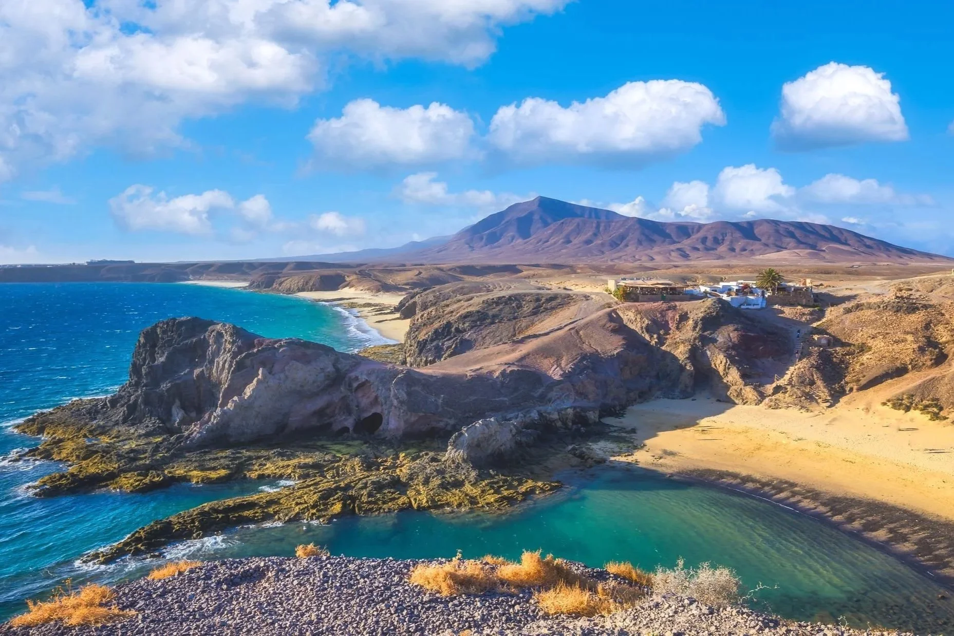 Volcanic coastline in Lanzarote with turquoise sea, rugged cliffs and mountain landscape