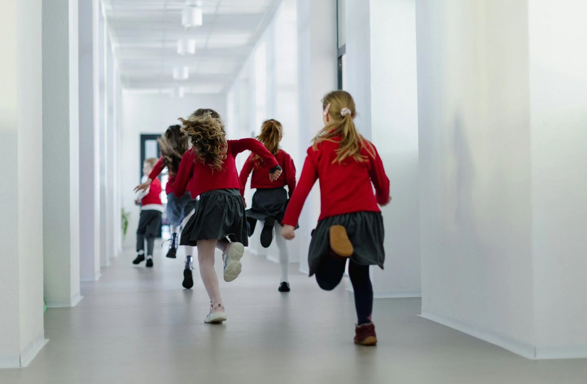 Children in red school uniform running through a bright school corridor for a back-to-school essentials feature