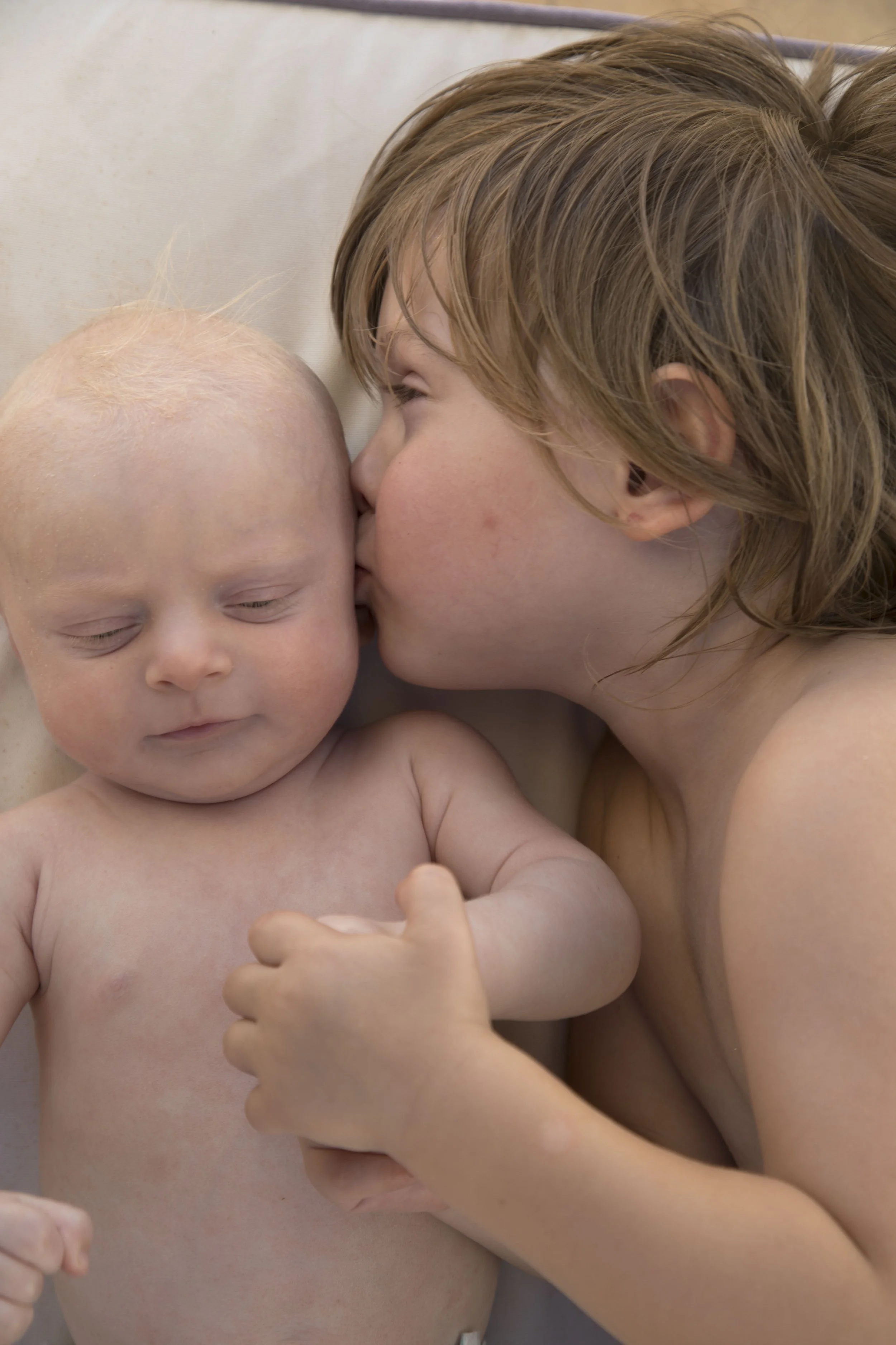 Young baby with an older sibling kissing his cheek after allergy symptoms had improved.