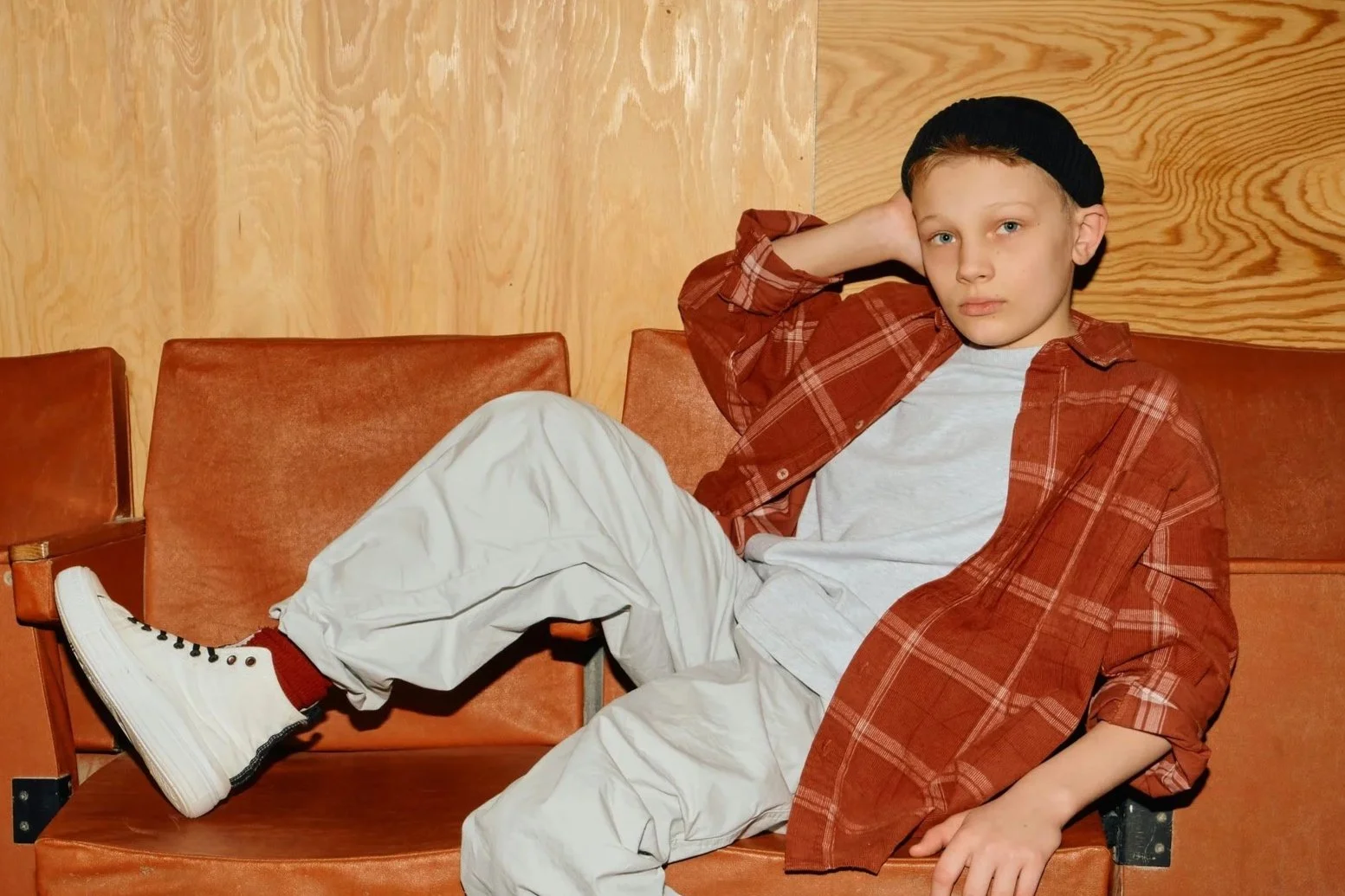 Boy sitting slouched across orange seats looking tired and unsettled
