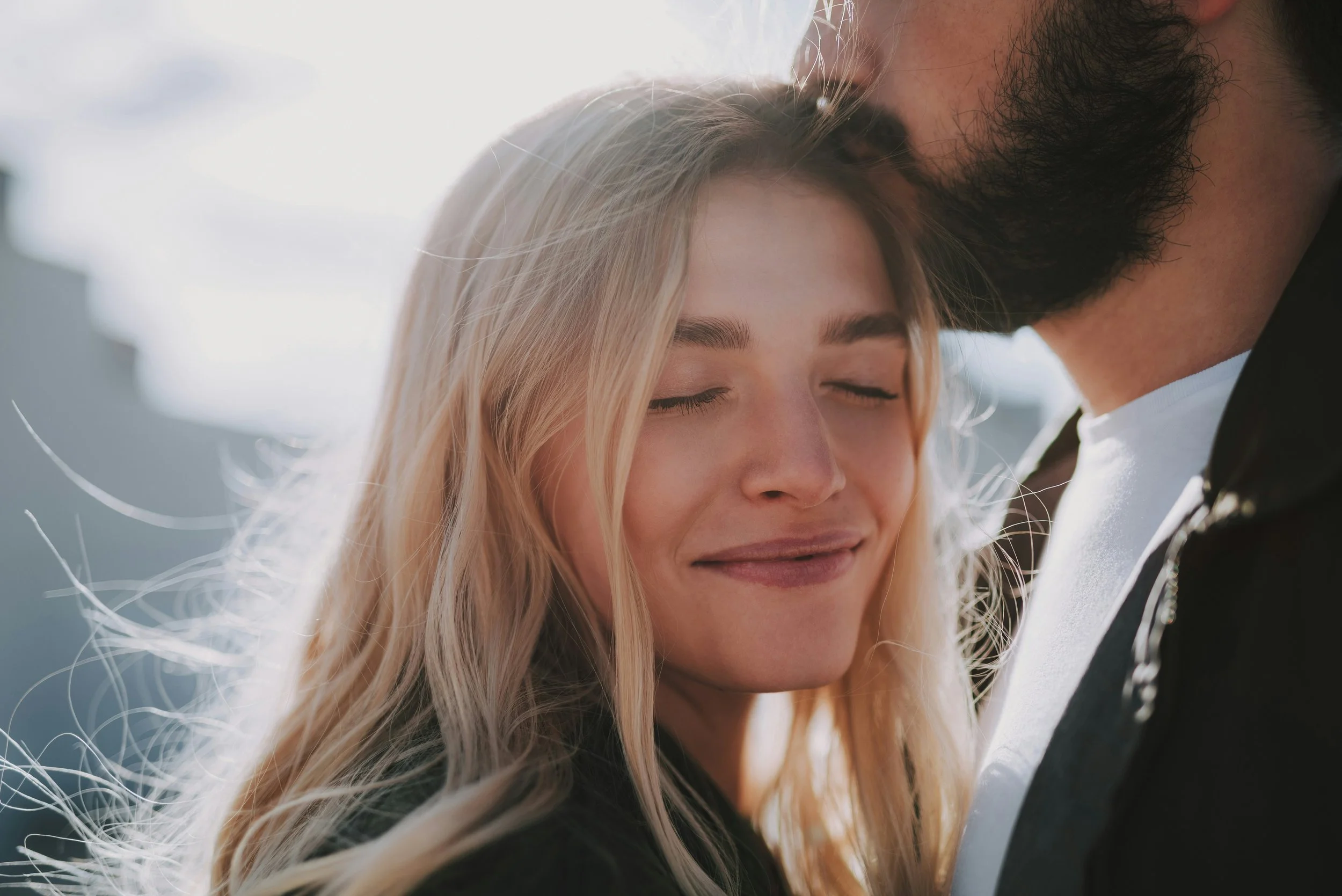 Woman leans in to her partner, smiling  with eyes closed taking in the moment