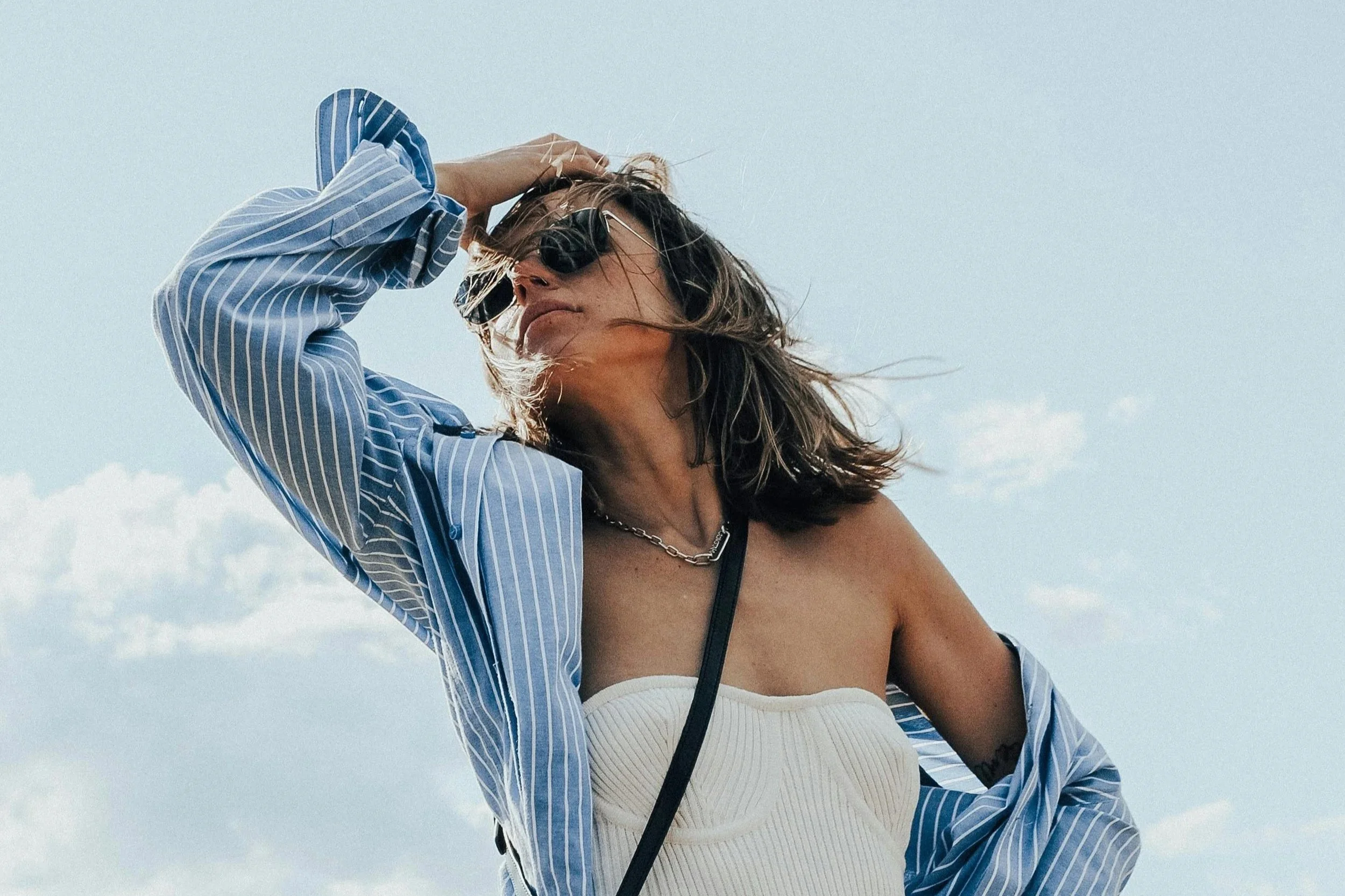 Woman wearing sunglasses outdoors in sunlight, with natural makeup and SPF for everyday protection