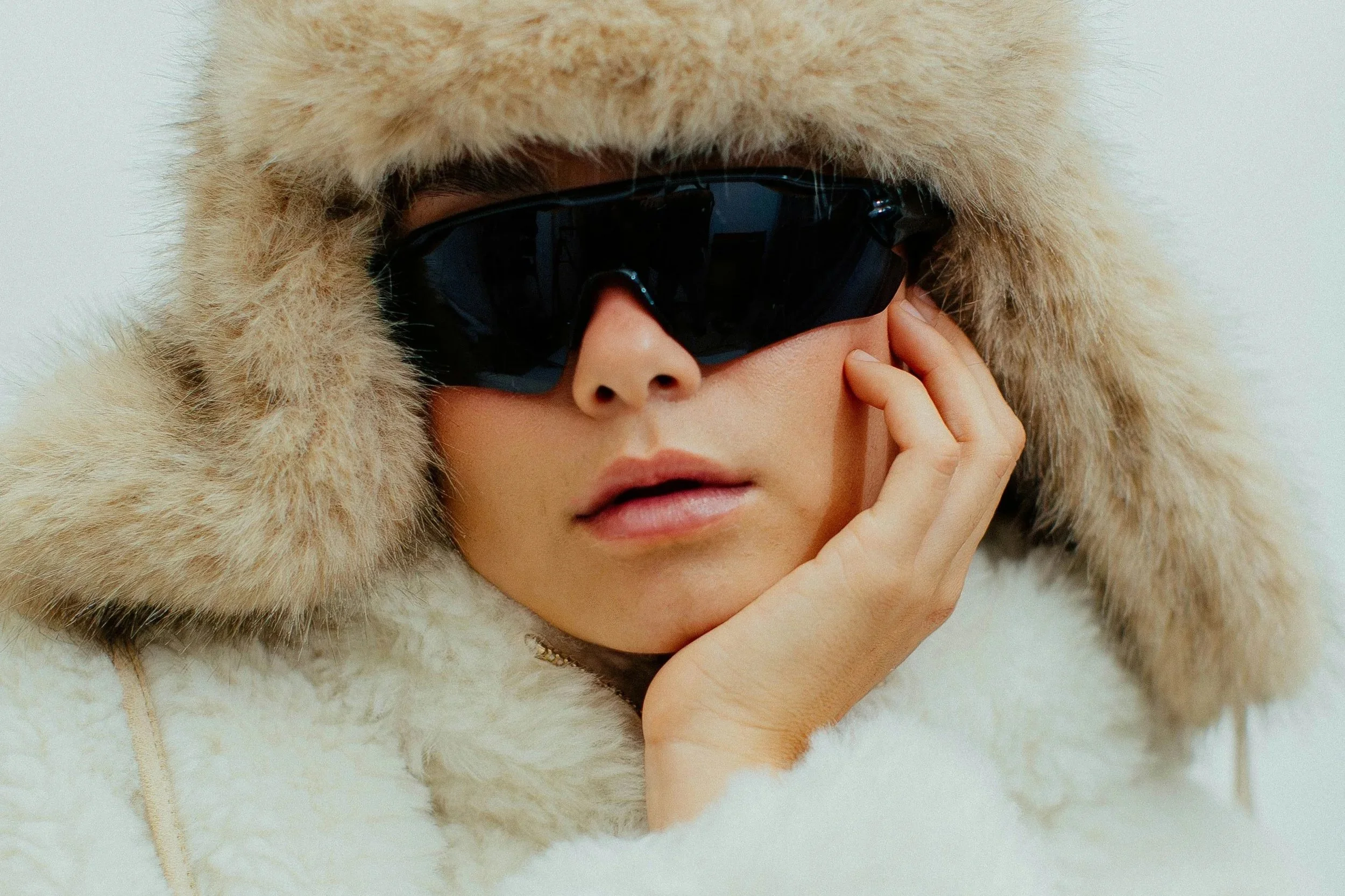 Ski goggles and fur-lined hat worn in alpine conditions, highlighting skincare and makeup challenges at altitude