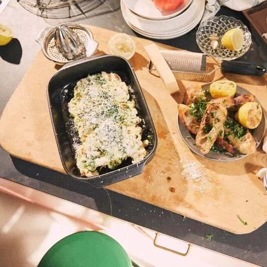Rosendahl oven-to-table cookware collection sits on a chopping board while a man prepares dinner