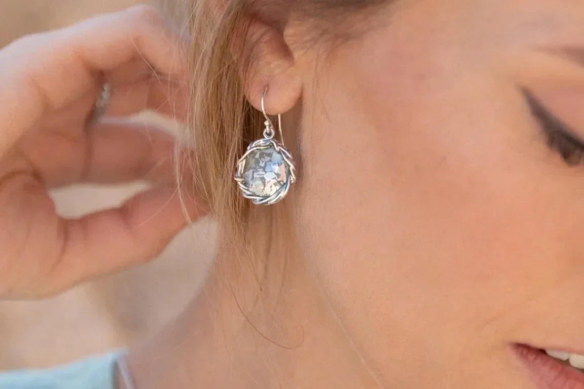 Close-up of a woman wearing a silver drop earring with a pale blue gemstone, styled for an elegant everyday jewellery look.
