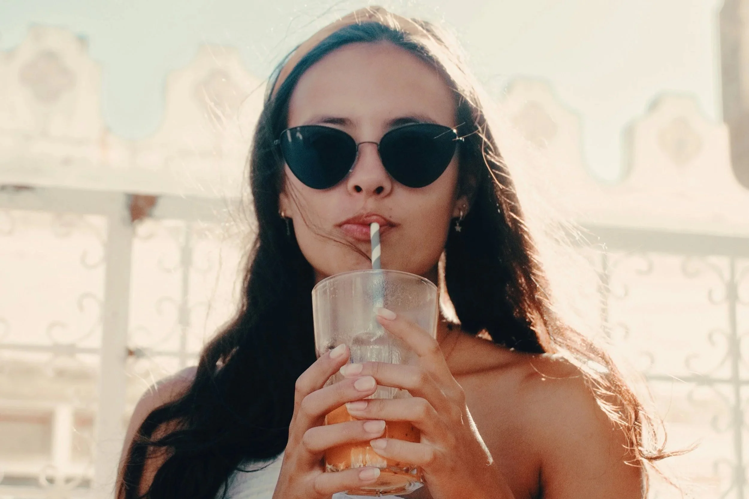 Woman enjoying a drink at golden hour with soft, natural holiday hair.