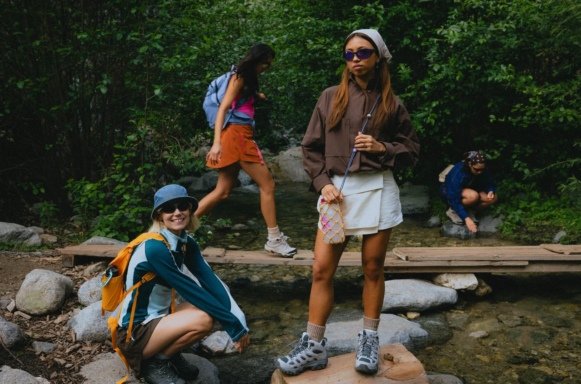 Women wearing fashion-forward SENIQ hiking outfits, technical jackets and outdoor footwear while exploring a woodland trail.