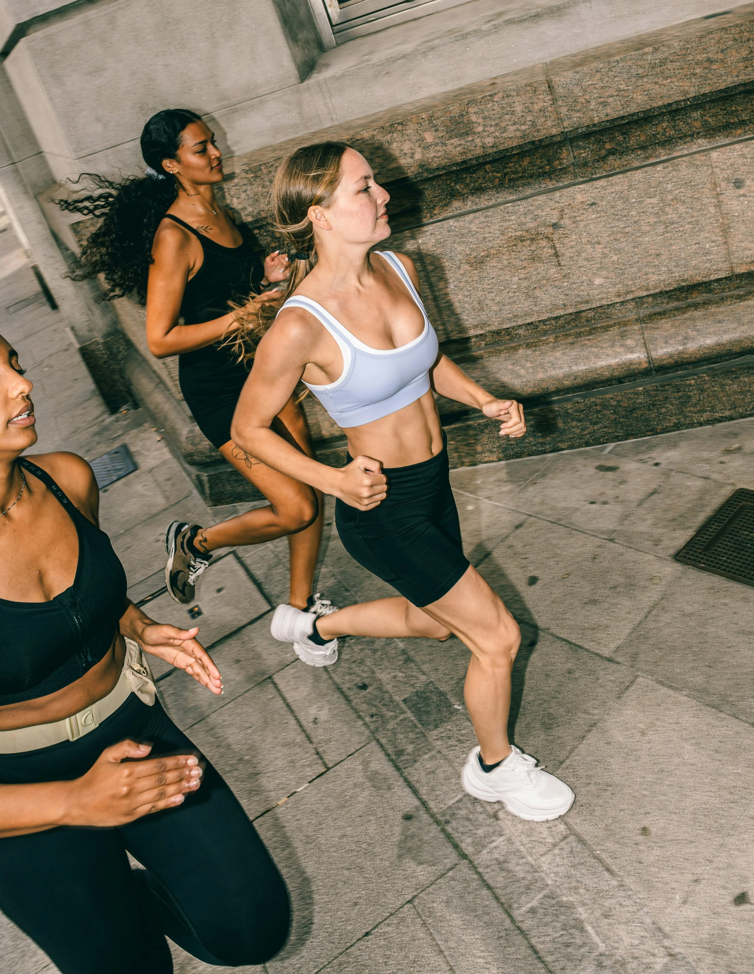 Women running together through city streets, illustrating the benefits of vigorous exercise for fitness, stress relief and cortisol regulation.