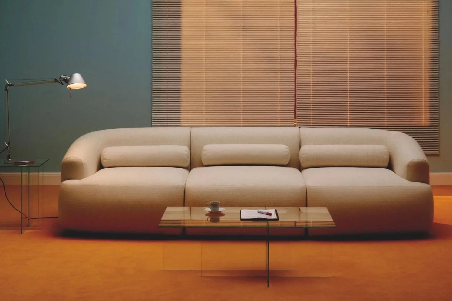 Curved neutral sofa with rounded edges in a warm-toned living room with soft lighting and wood flooring by Westwing