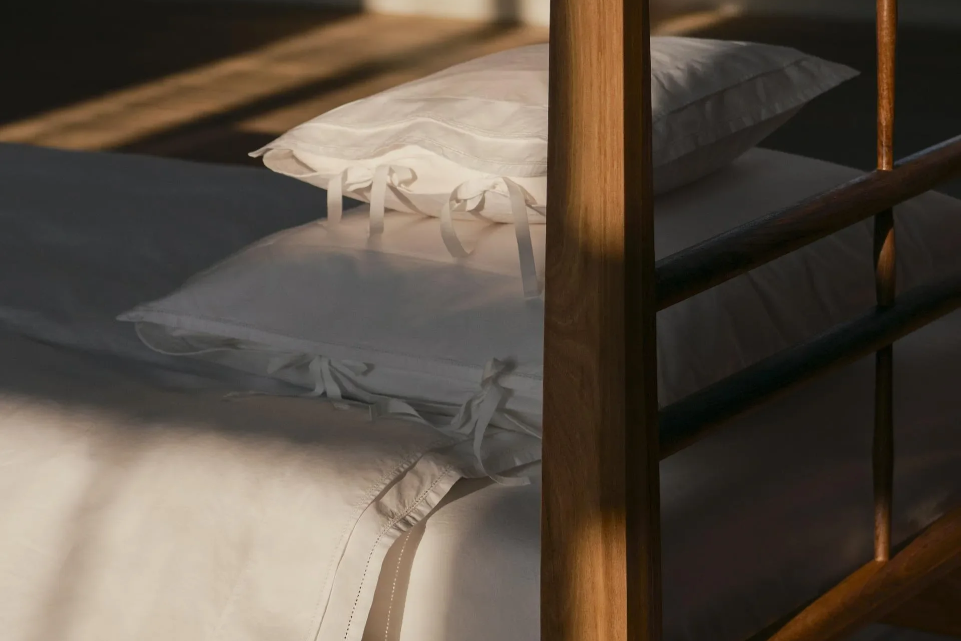 Broderie anglaise bedlinen styled on a wooden bed in soft morning light.