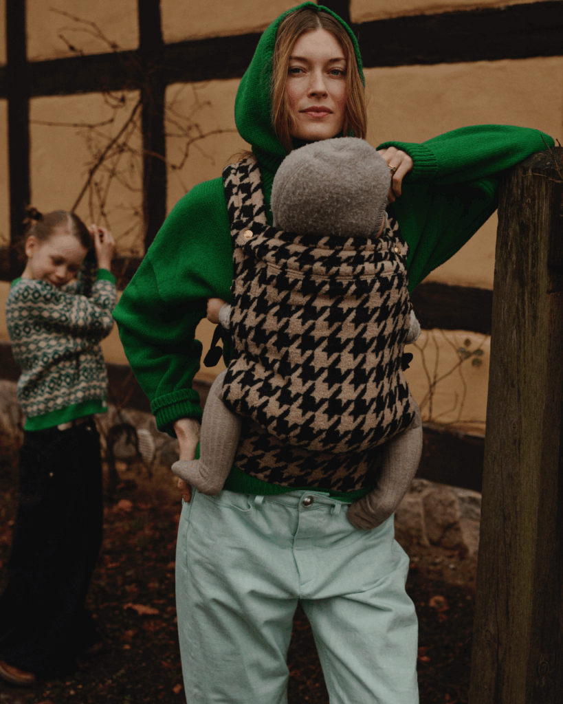 Mother wearing an Artipoppe Zeitgeist houndstooth baby carrier with her baby outdoors