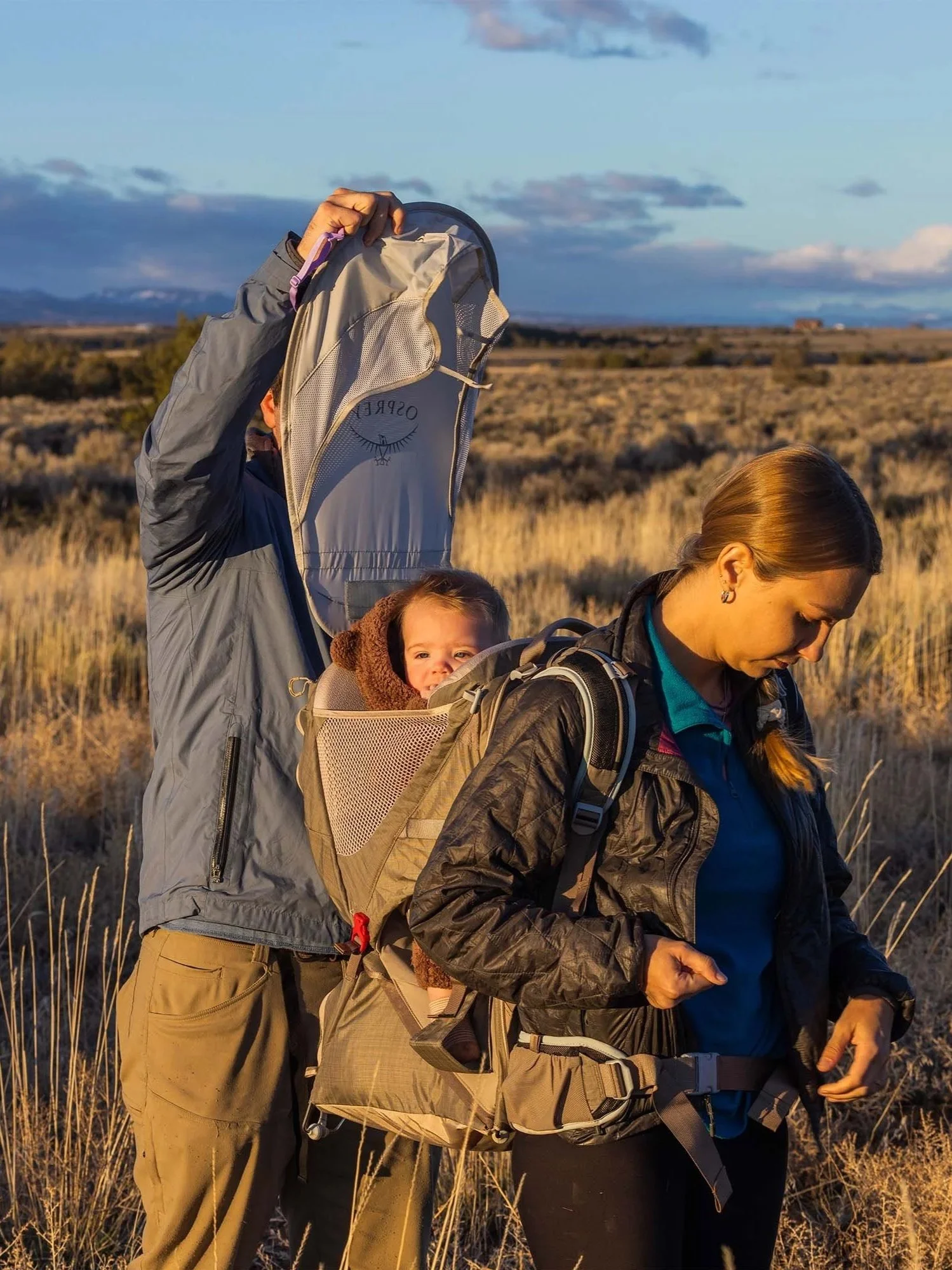 Parents hiking outdoors with a toddler in an Osprey Poco LT backpack child carrier