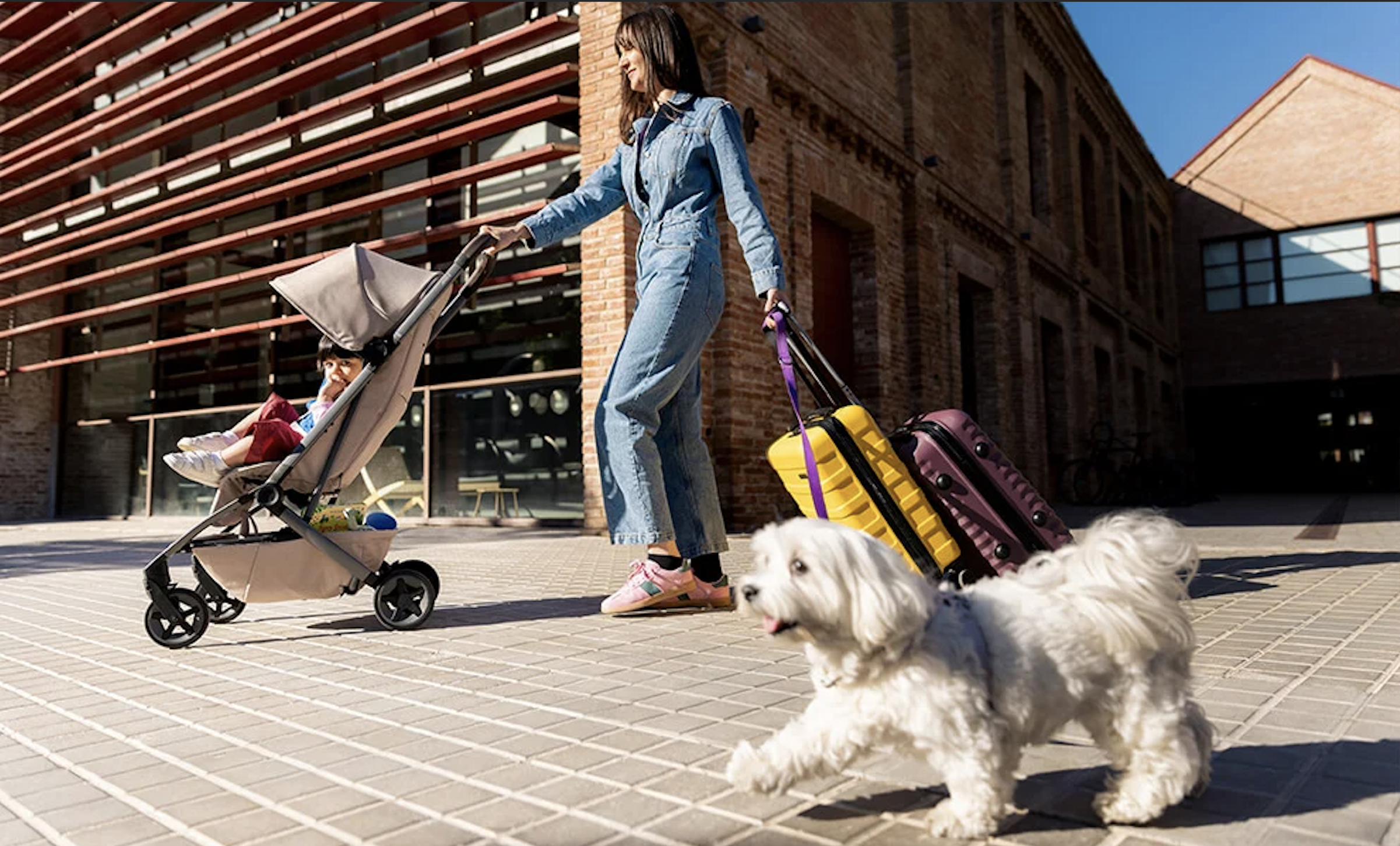 Parent pushing the Joolz Aer2 stroller beside suitcases outdoors highlighting the compact travel-friendly design