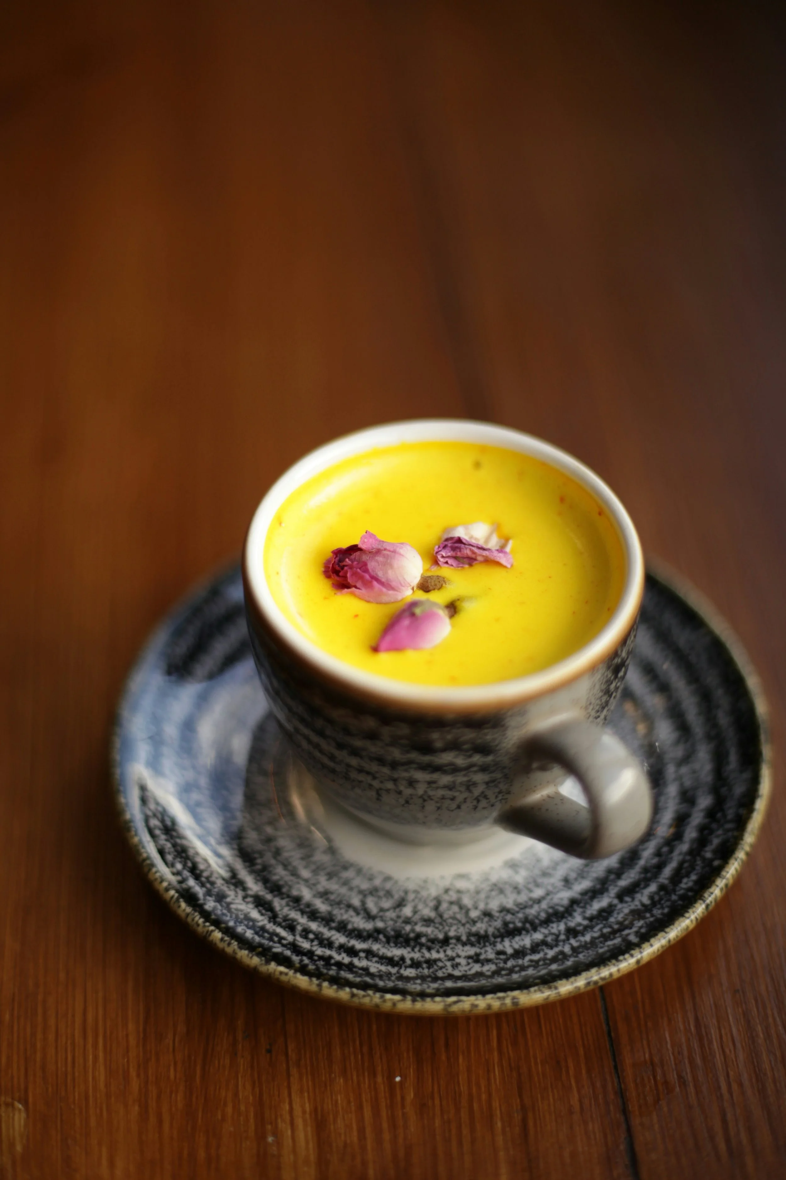Cup of golden turmeric milk on a wooden table, a traditional drink associated with Ayurvedic wellness practices