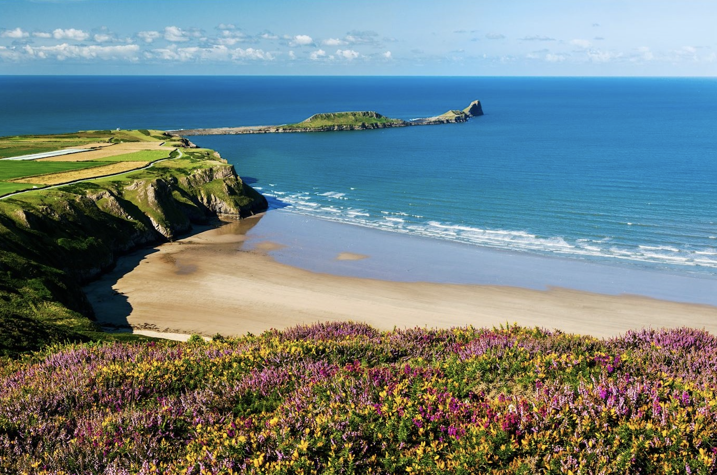 Rhossili Bay on the Gower Peninsula with sweeping sands, dramatic cliffs and Worm's Head in the distance.