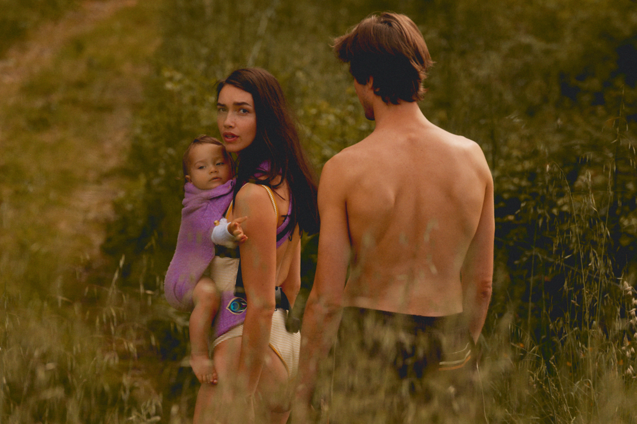 Mother carrying baby in a purple baby carrier during a stylish family summer holiday wearing a Artipoppe zeitgeist carrier