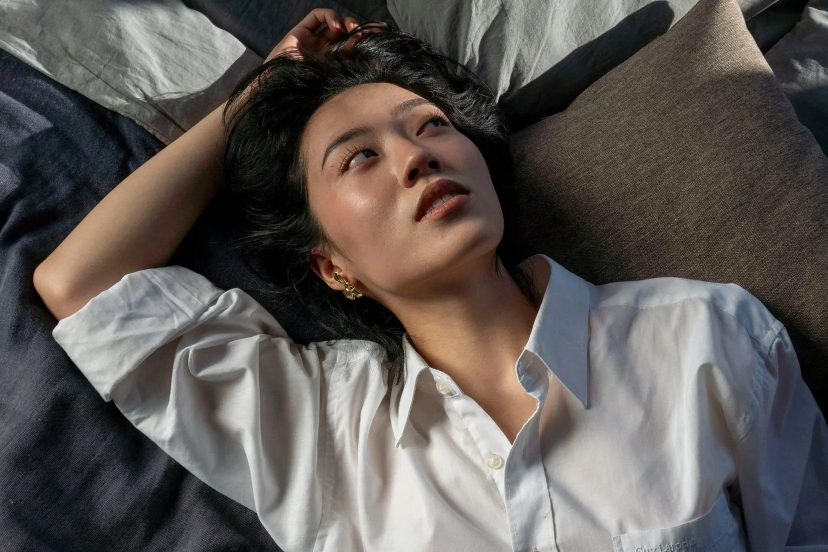 Woman with glowing skin lying on a bed, illustrating skin renewal and regenerative skincare after microneedling with exosomes