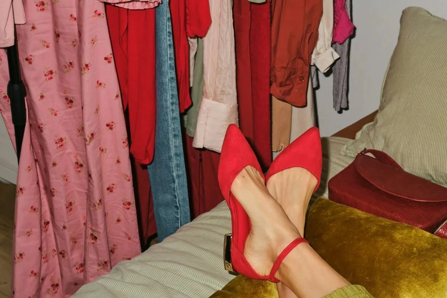 Cluttered bedroom with overflowing clothes rail and red heels on bed showing limited storage space in a UK home