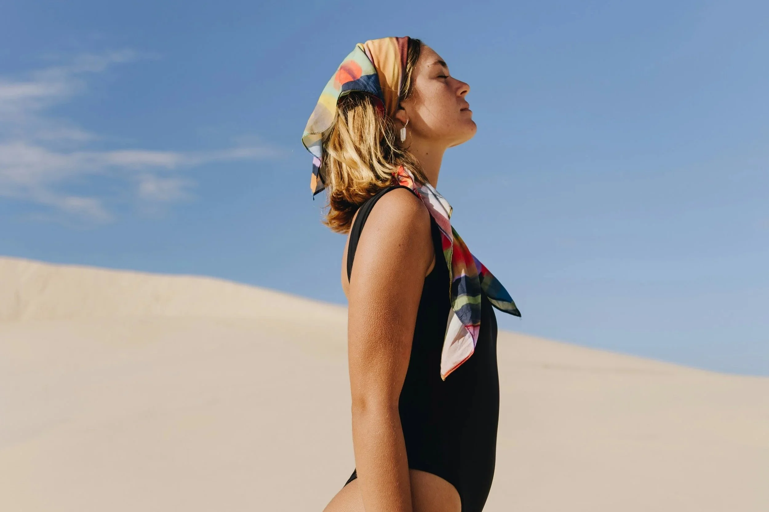 Woman wearing a colourful headscarf in the sun for a heat-proof holiday makeup edit.