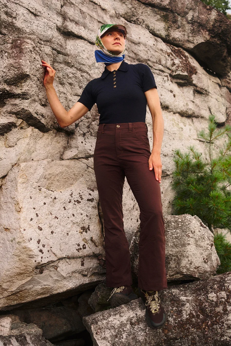 Woman wearing a navy collared top and tailored brown outdoor trousers from fashion-led hiking brand Hikerkind.