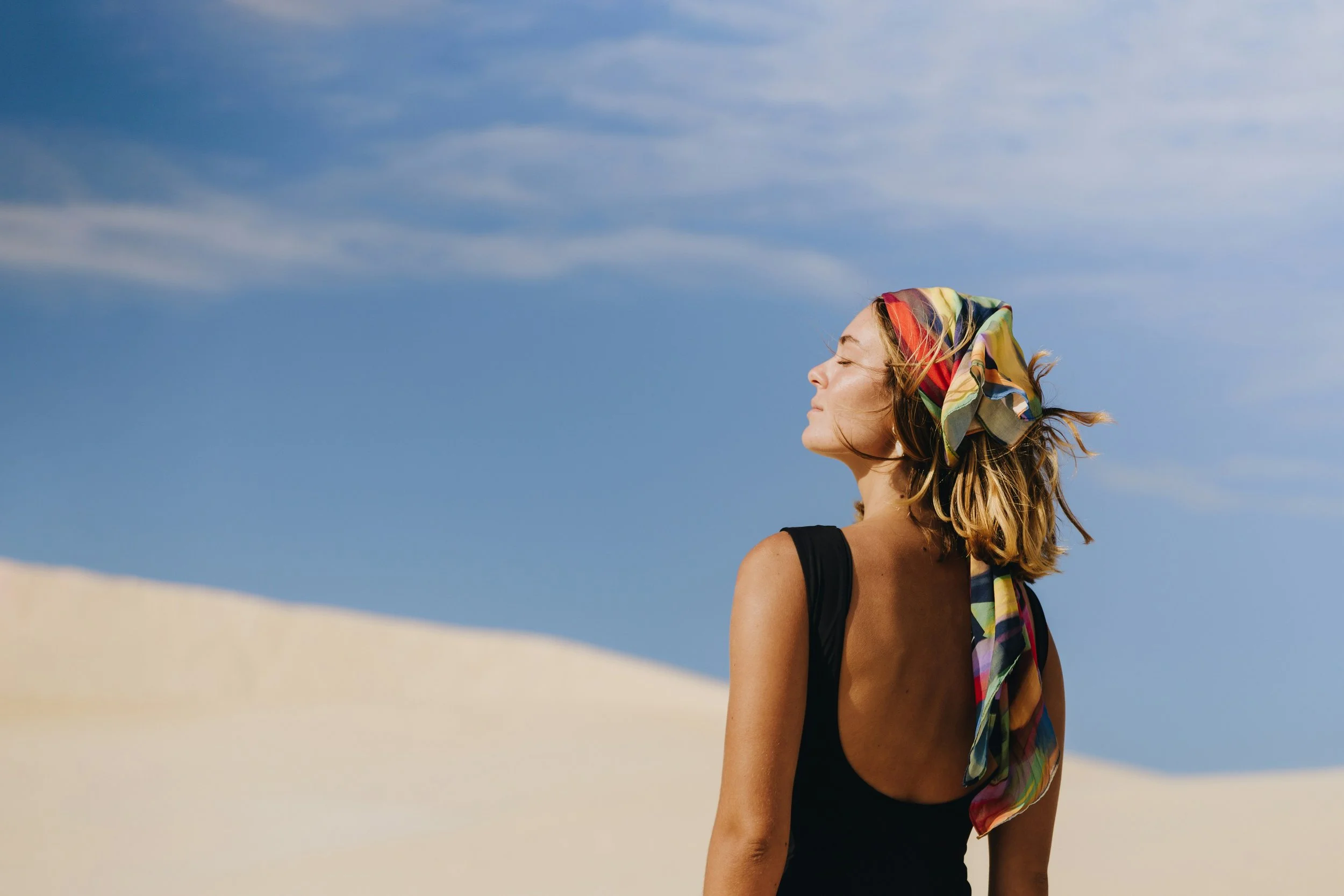 Woman in a colourful headscarf enjoying the sunshine on holiday.