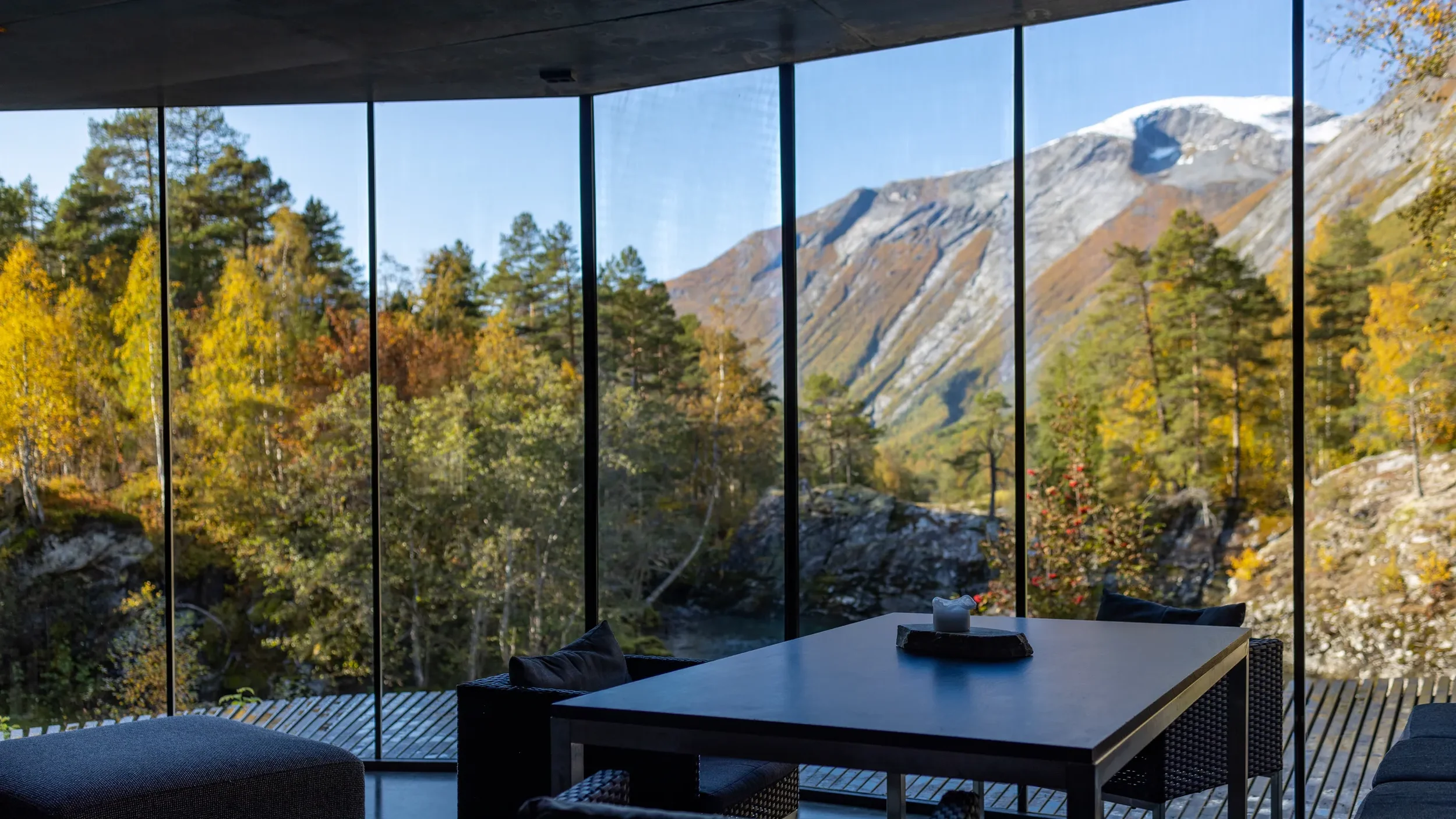 Modern cabin perched on rocky cliff above Norwegian fjord, surrounded by pine trees and dramatic coastline at Juvet Landscape Hotel