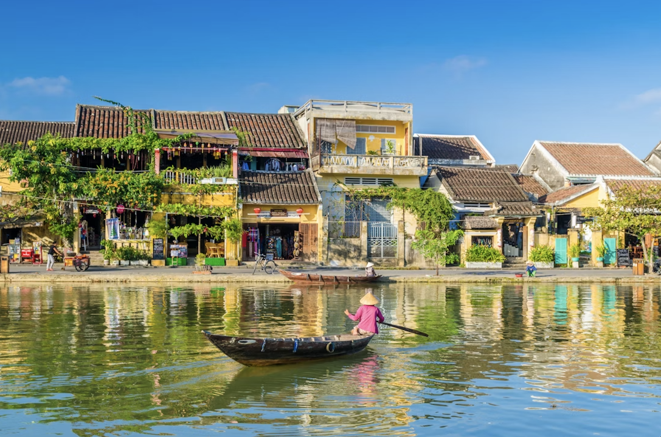 Hoi An, Vietnam riverside old town with lantern-lit buildings and traditional wooden boat