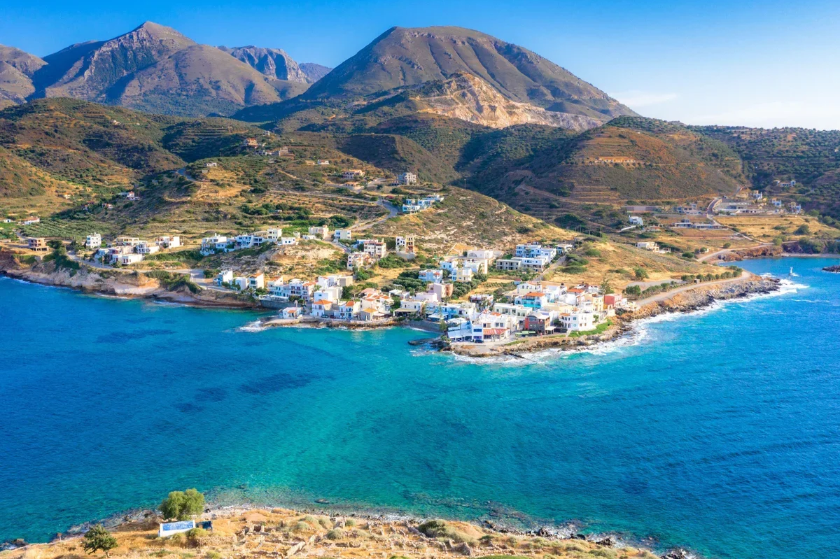 Coastal village beneath the mountains beside the blue sea in Crete.