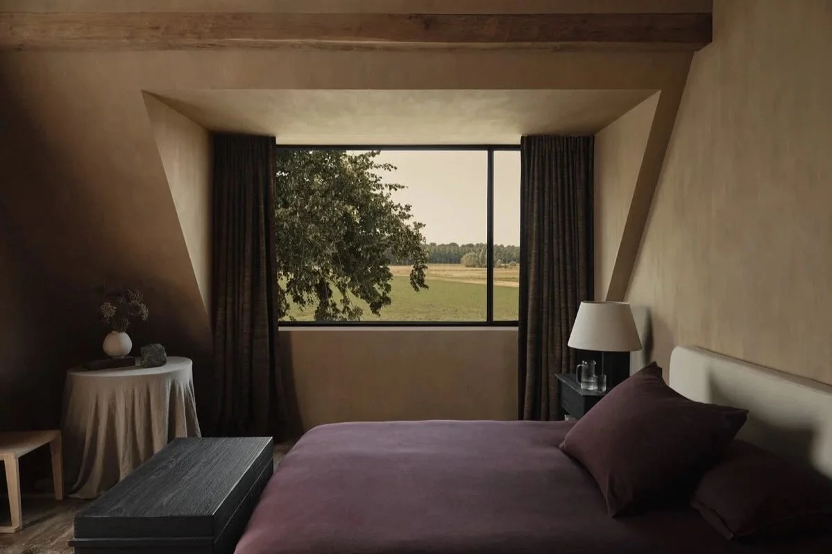 Zara Home bedroom with plastered walls, linen bedding, and a view out the window of the countryside