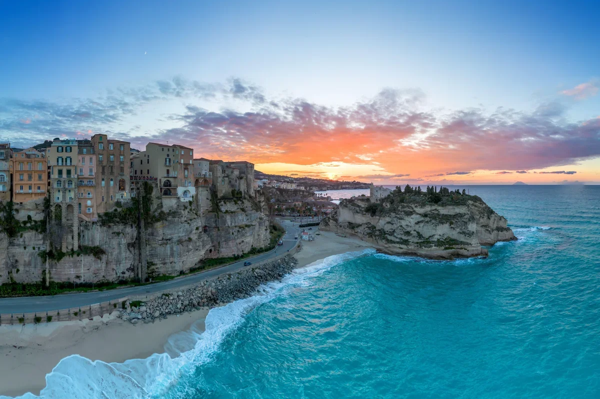 Tropea, Italy at sunset with cliff-top old town overlooking turquoise Tyrrhenian Sea and sandy beach in spring