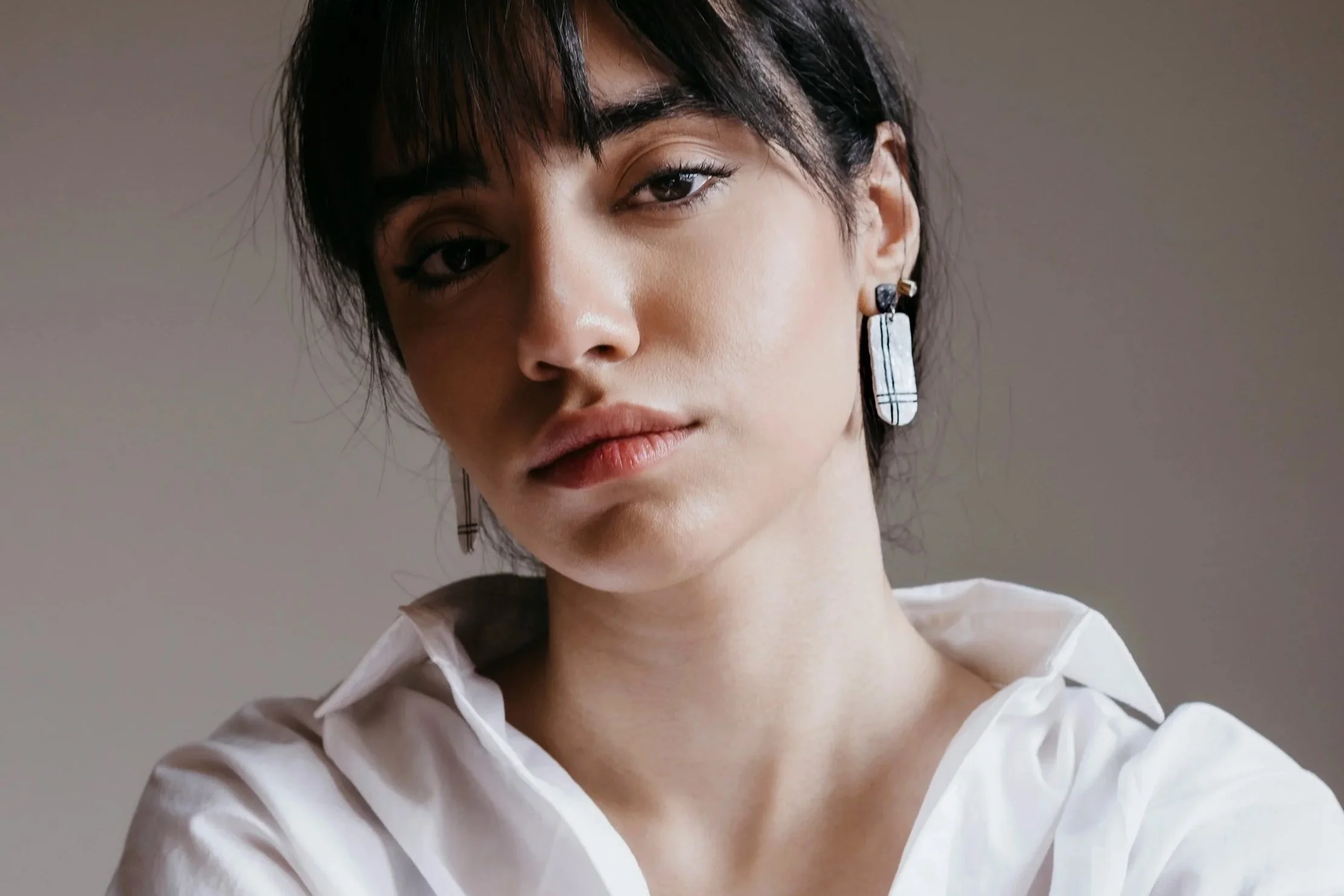 Woman wearing a white shirt shows off her jawline after having Thermage FLX