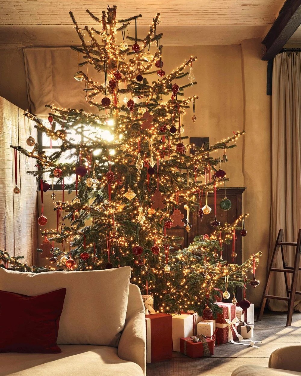 Traditional Christmas tree with red and gold decorations, lights and wrapped gifts