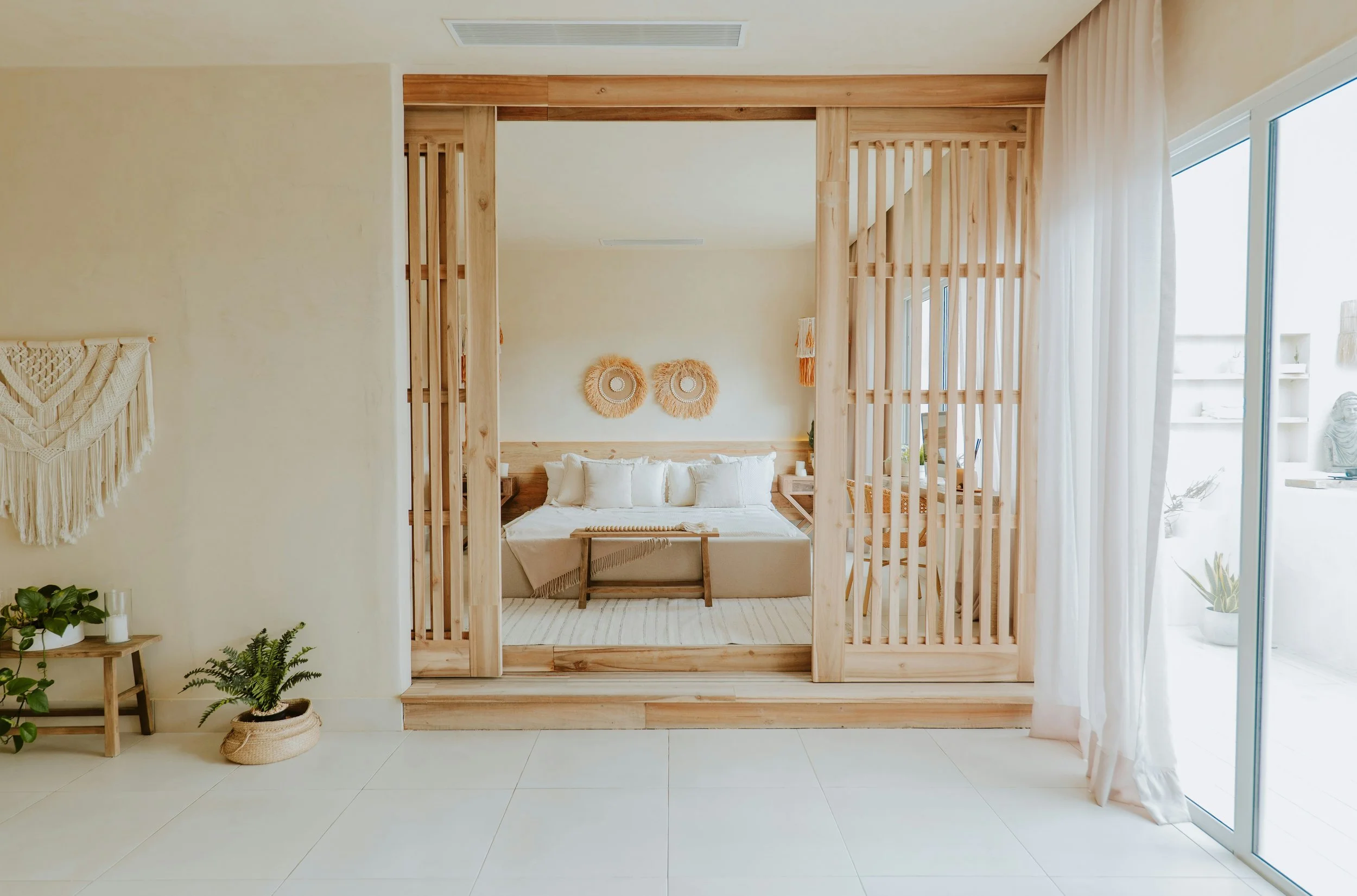 Light-filled neutral interior with linen curtains, natural wood detailing and tactile minimalist decor inspired by biophilic living