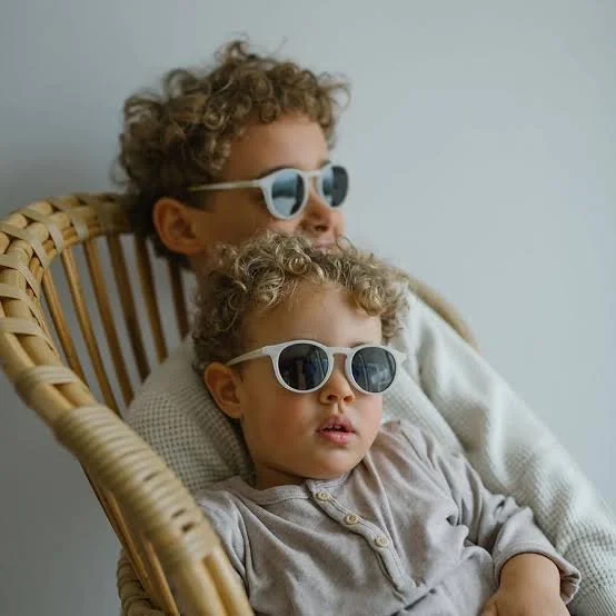 Two brothers sit together on a chair wearing Leo Sun Children's Sunglasses