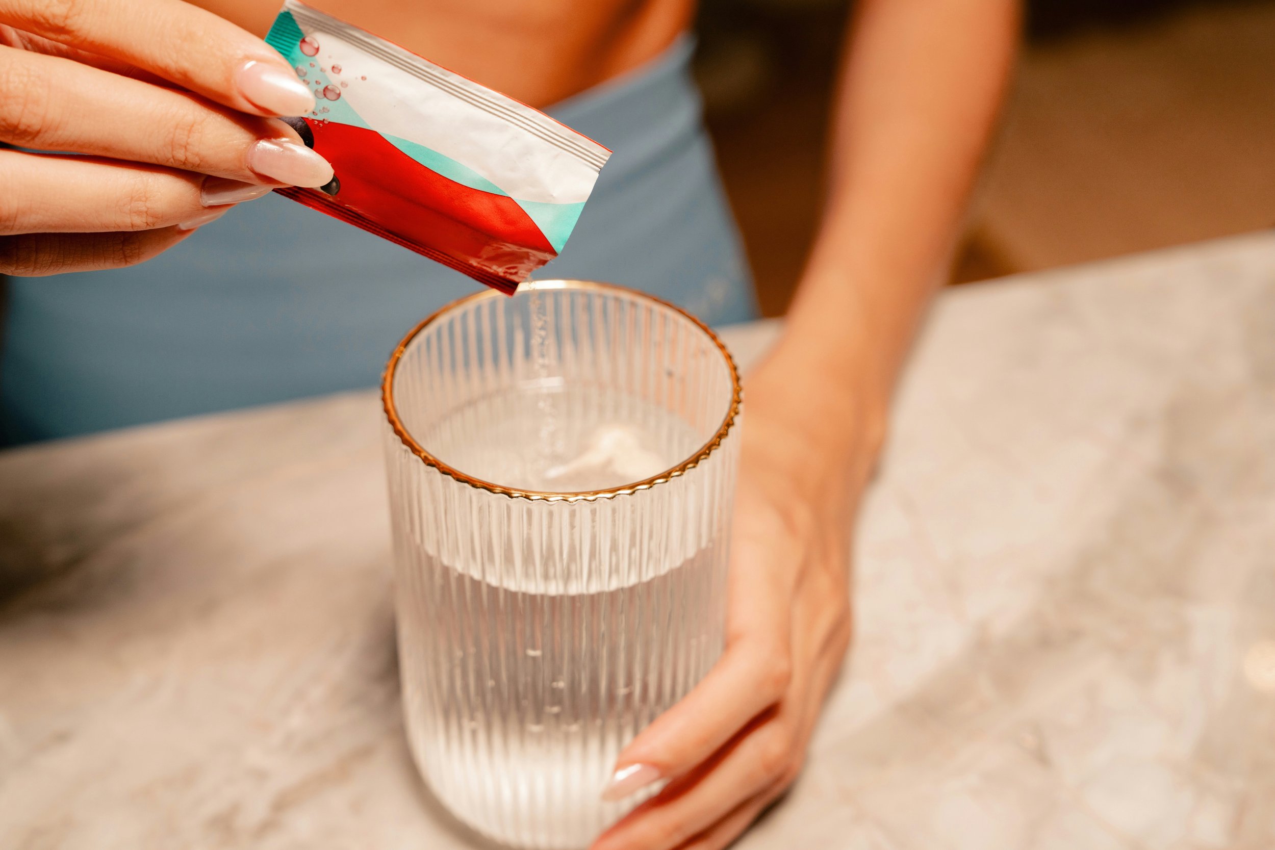 Electrolyte supplement sachet being poured into water glass