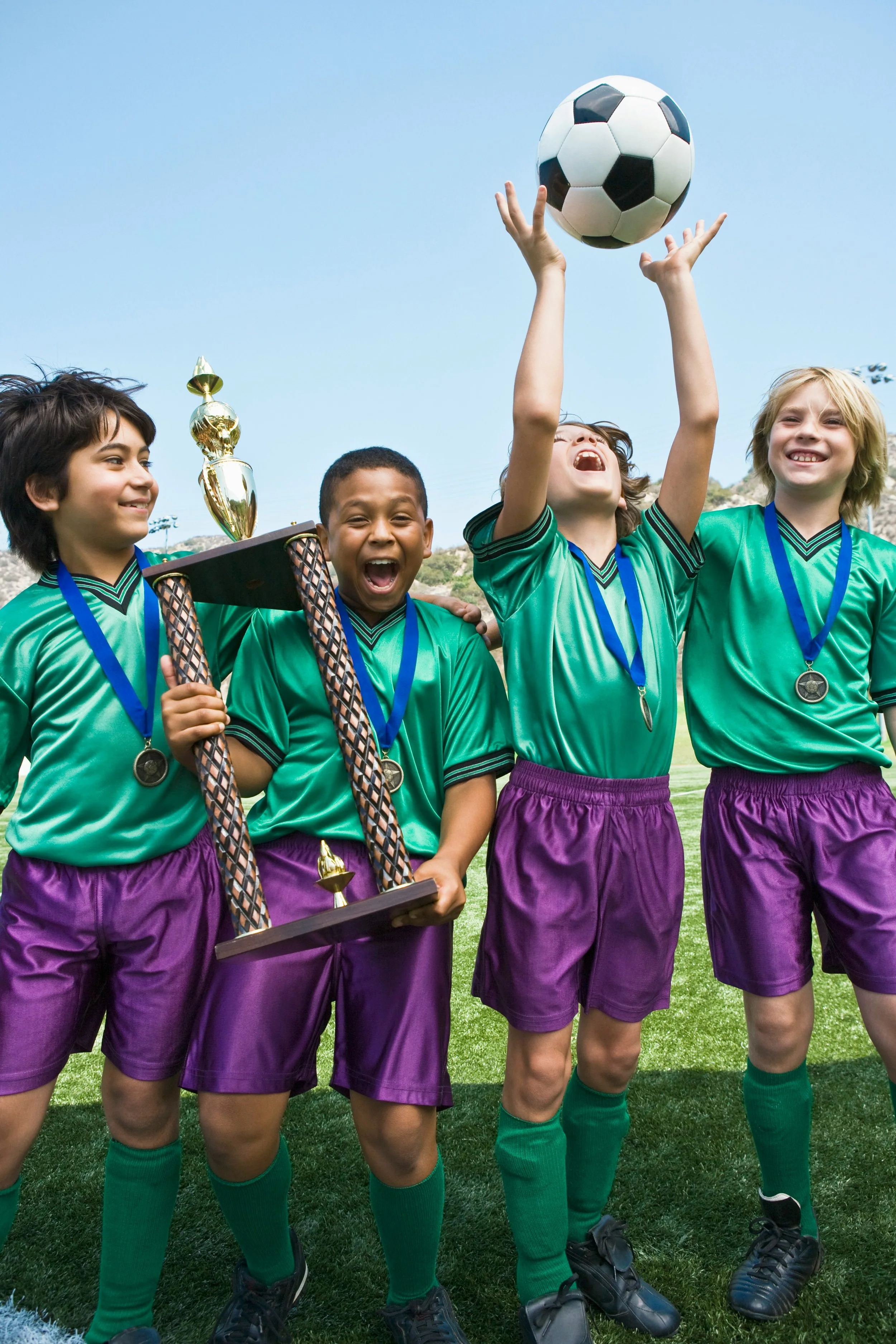 Young football team celebrating a win with medals and a trophy, illustrating achievement and childhood competition.
