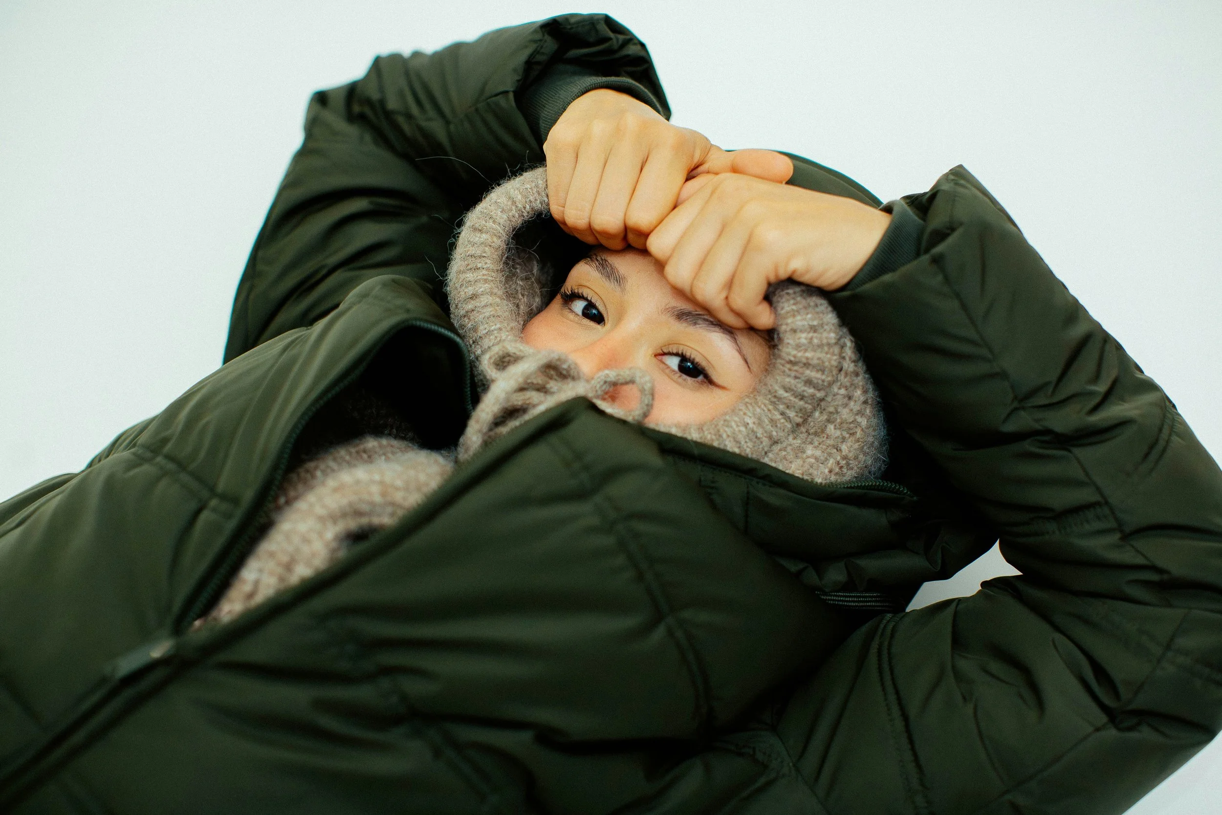 Cold-weather mountain layering with padded jacket and scarf, winter skin protection focus