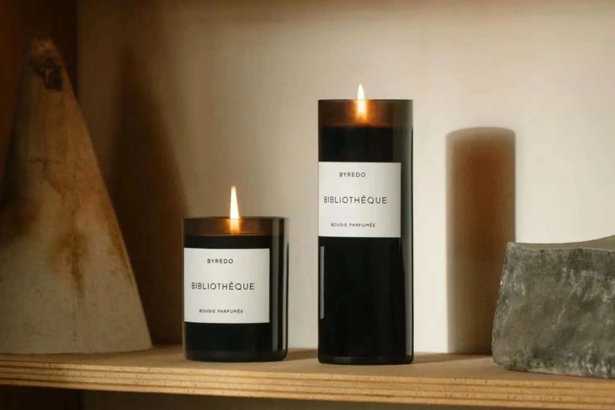 Byredo Bibliothèque scented candles and room spray styled on a wooden surface with warm candlelight