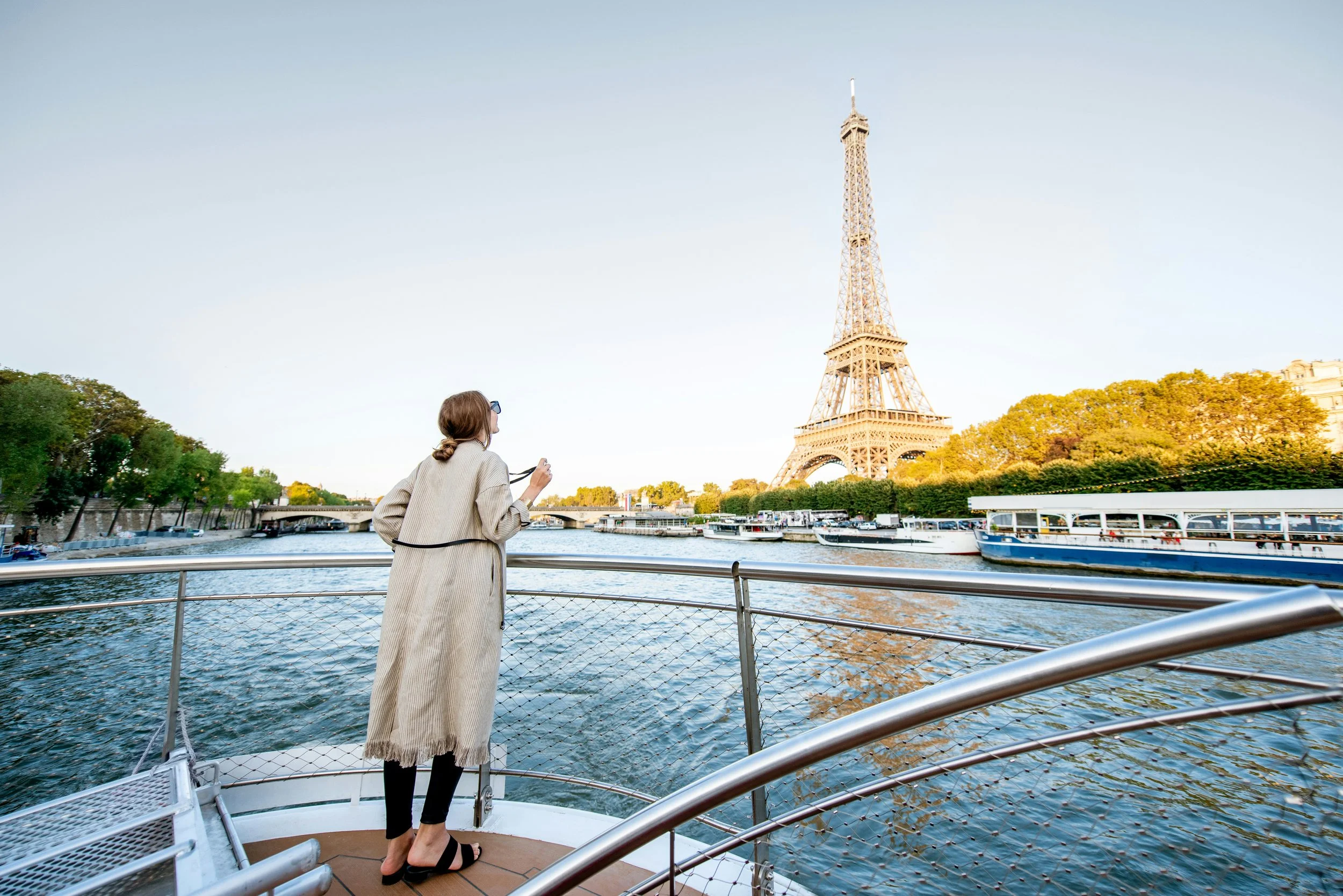 Woman standing on a boat looking at the Eiffel Tower along the River Seine in Paris