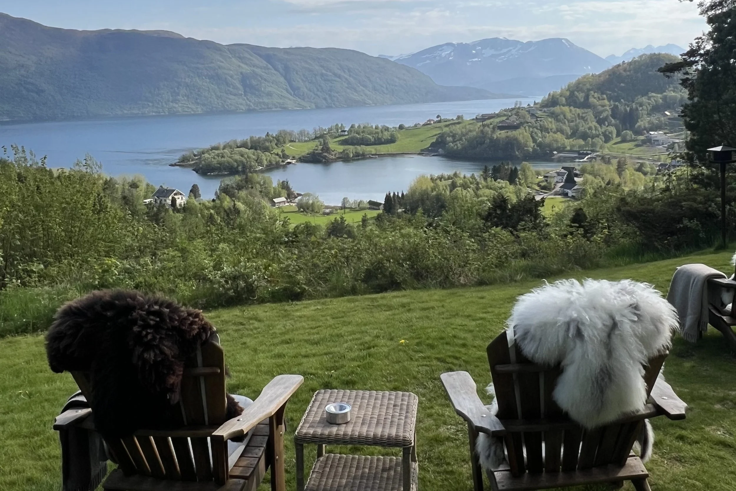 Peaceful fjord landscape with wooden chairs overlooking water, rolling hills and distant mountains at Storfjord Hotel