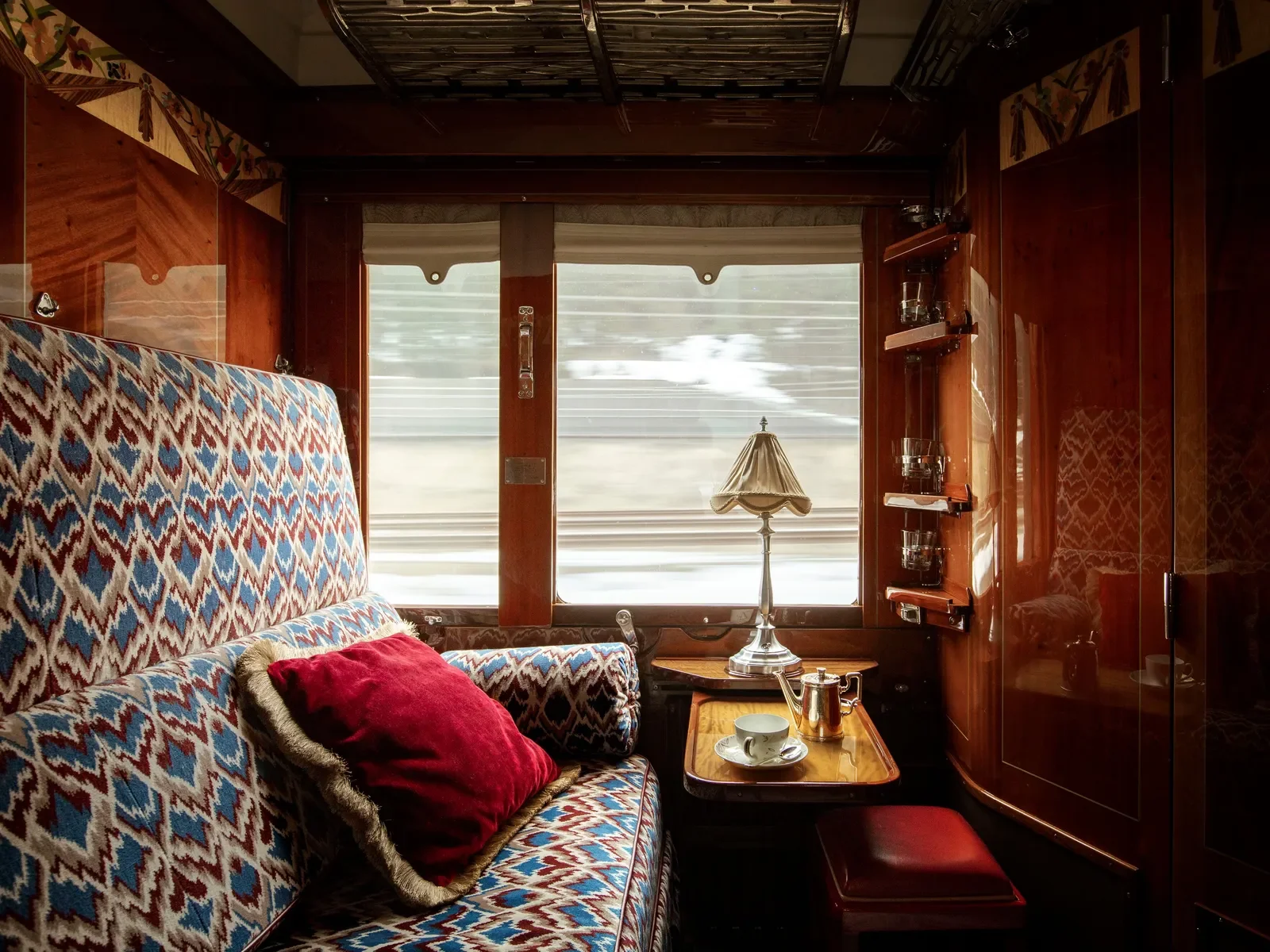 Historic Cabin aboard the Venice Simplon-Orient-Express, featuring patterned upholstery, polished wood and vintage railway interiors.