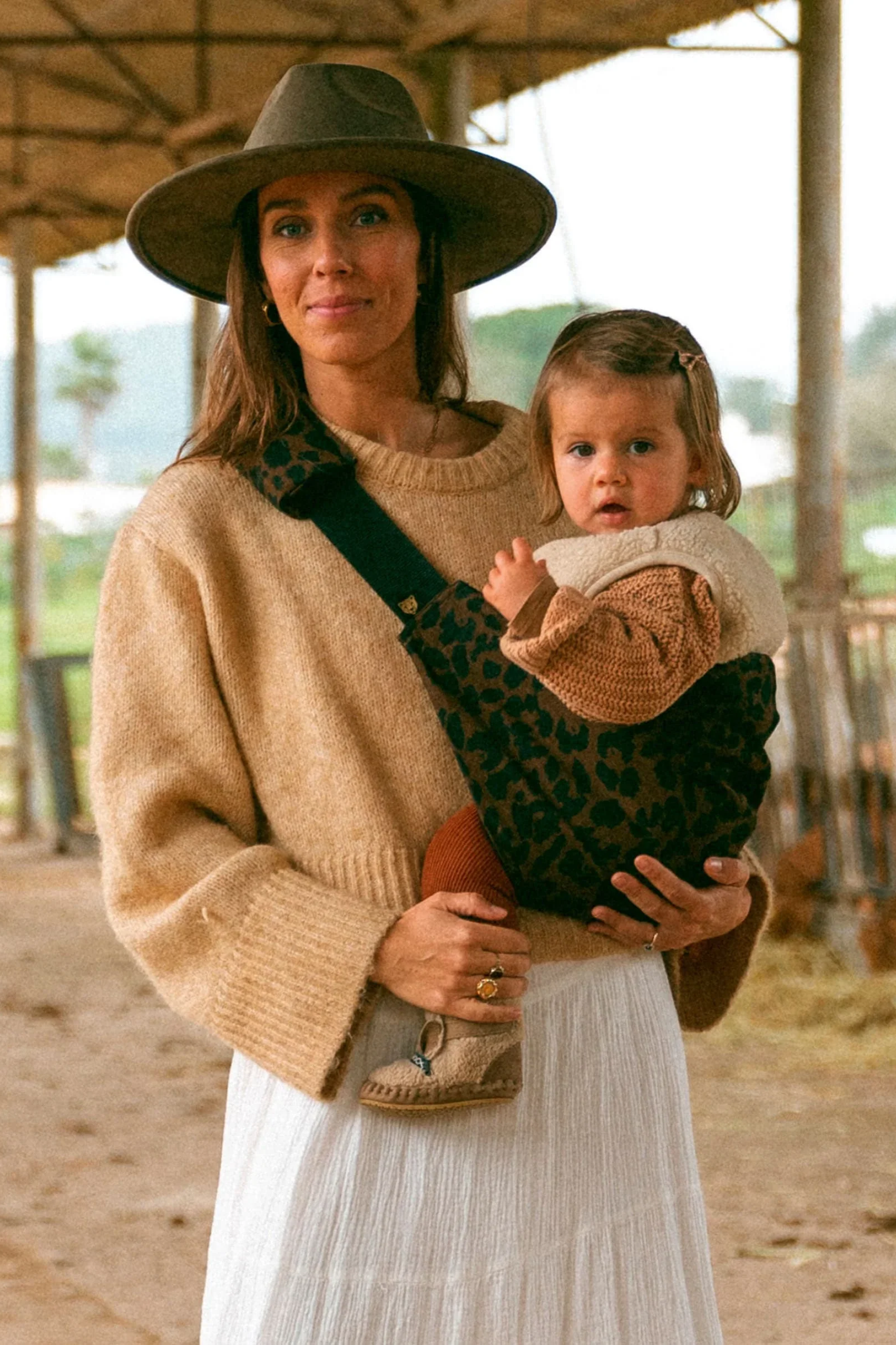 Mother carrying her toddler on her hip in a leopard-print Wildride toddler carrier