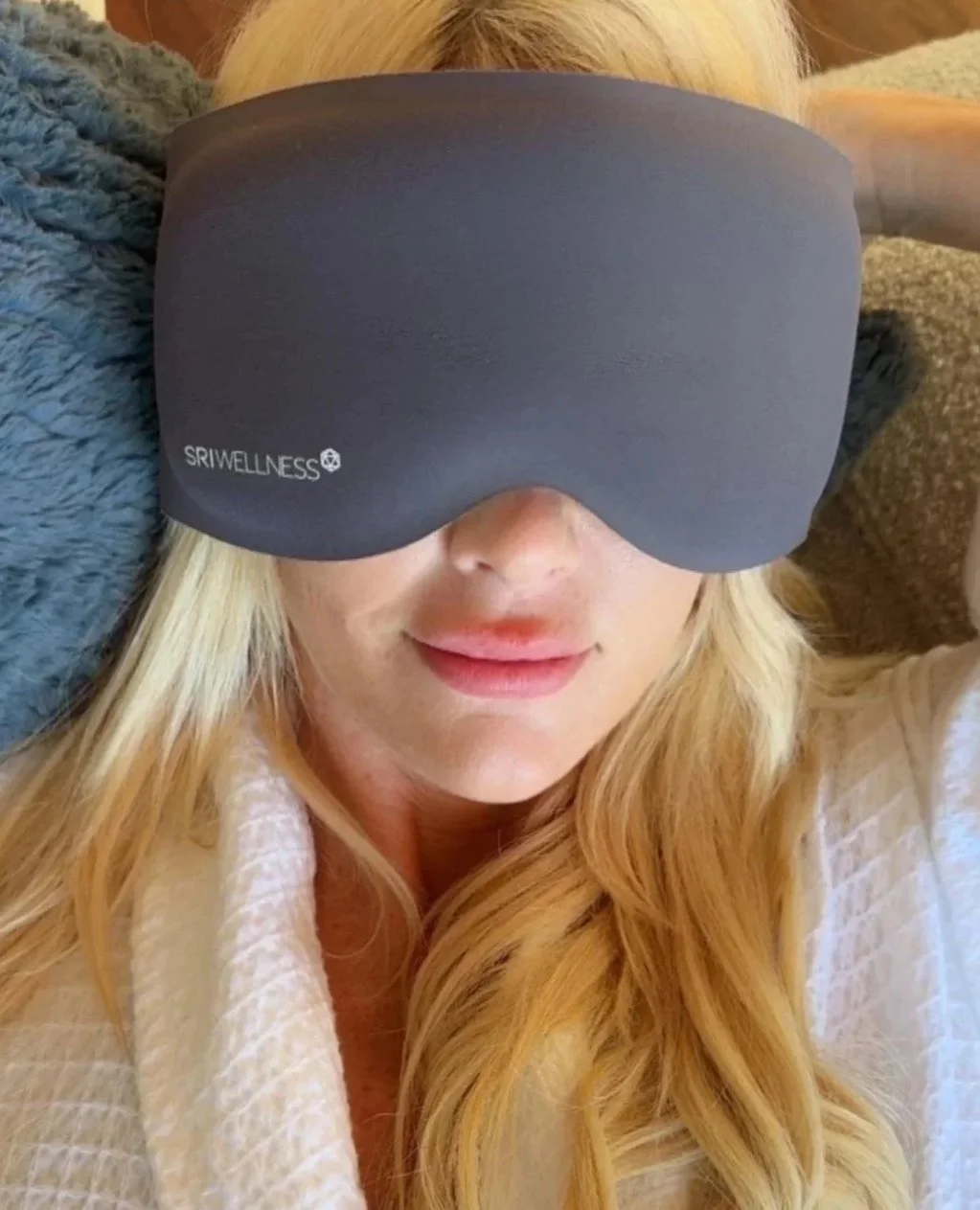 Woman wearing the grey SRI Wellness Orca Sleep Mask while lying in bed