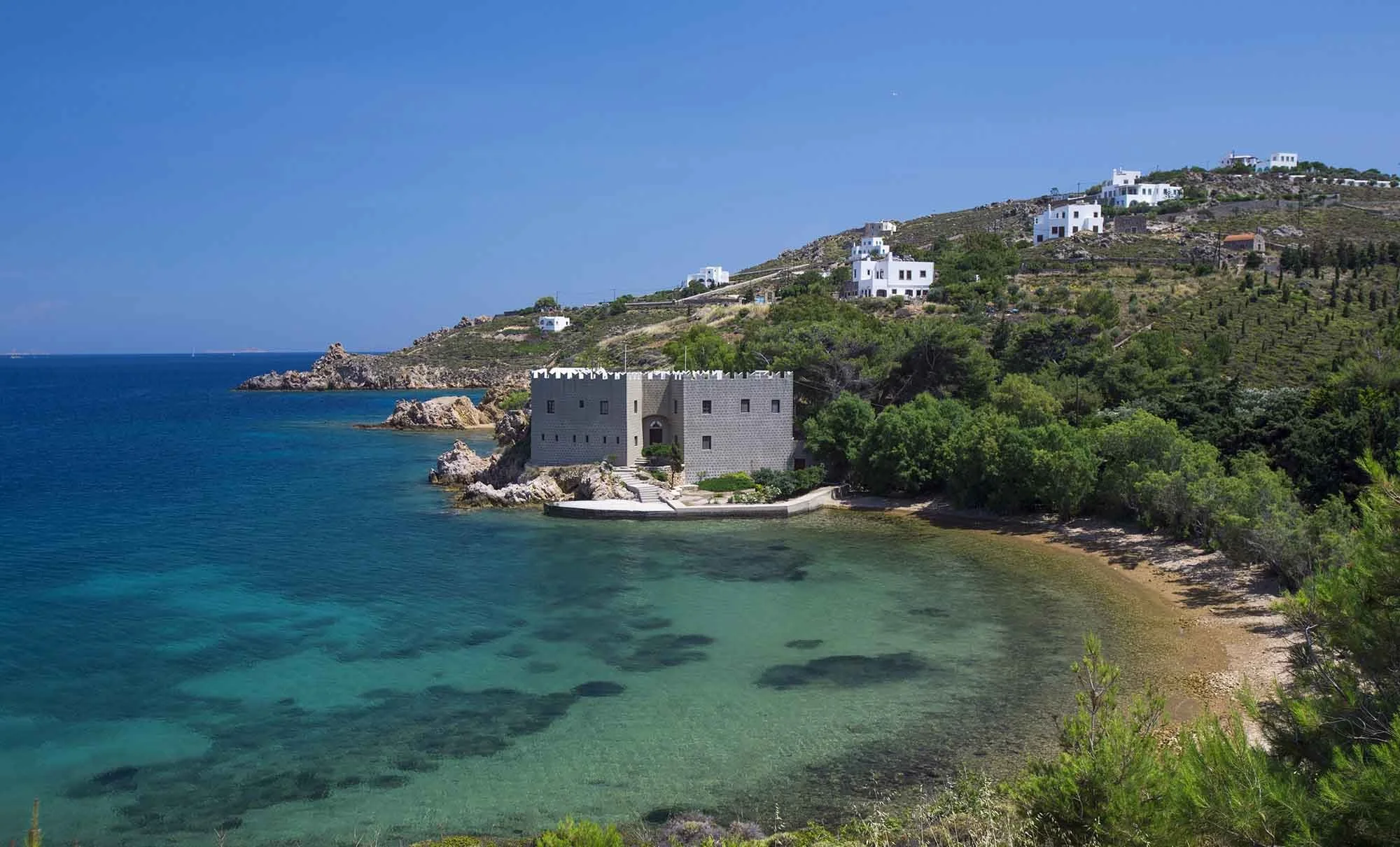 Coastal view of Patmos in Greece with a historic stone building overlooking turquoise Aegean waters