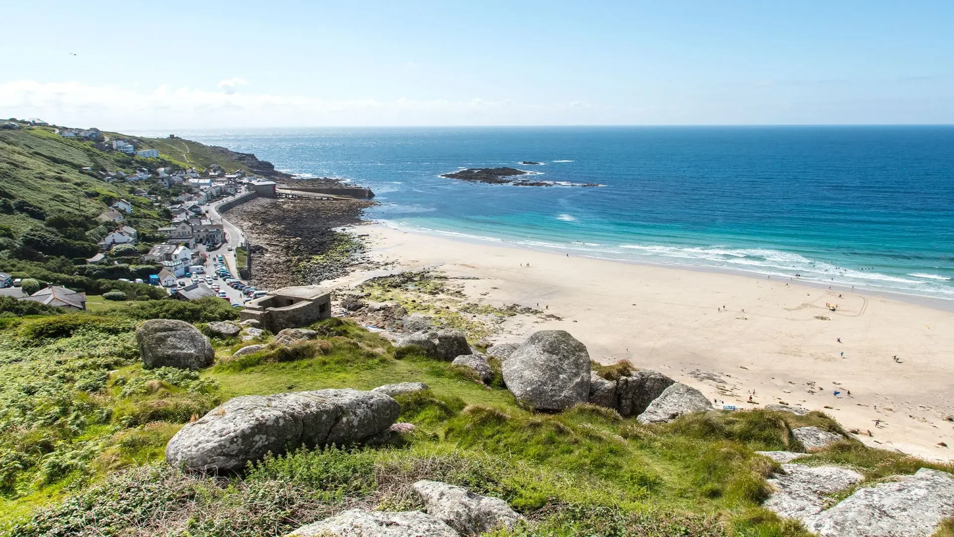 Sennen Beach in west Cornwall with white sand, turquoise water and dramatic coastal scenery.