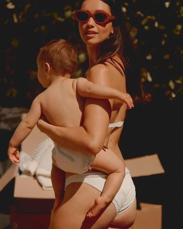 Mother carrying baby poolside during a luxury family summer holiday